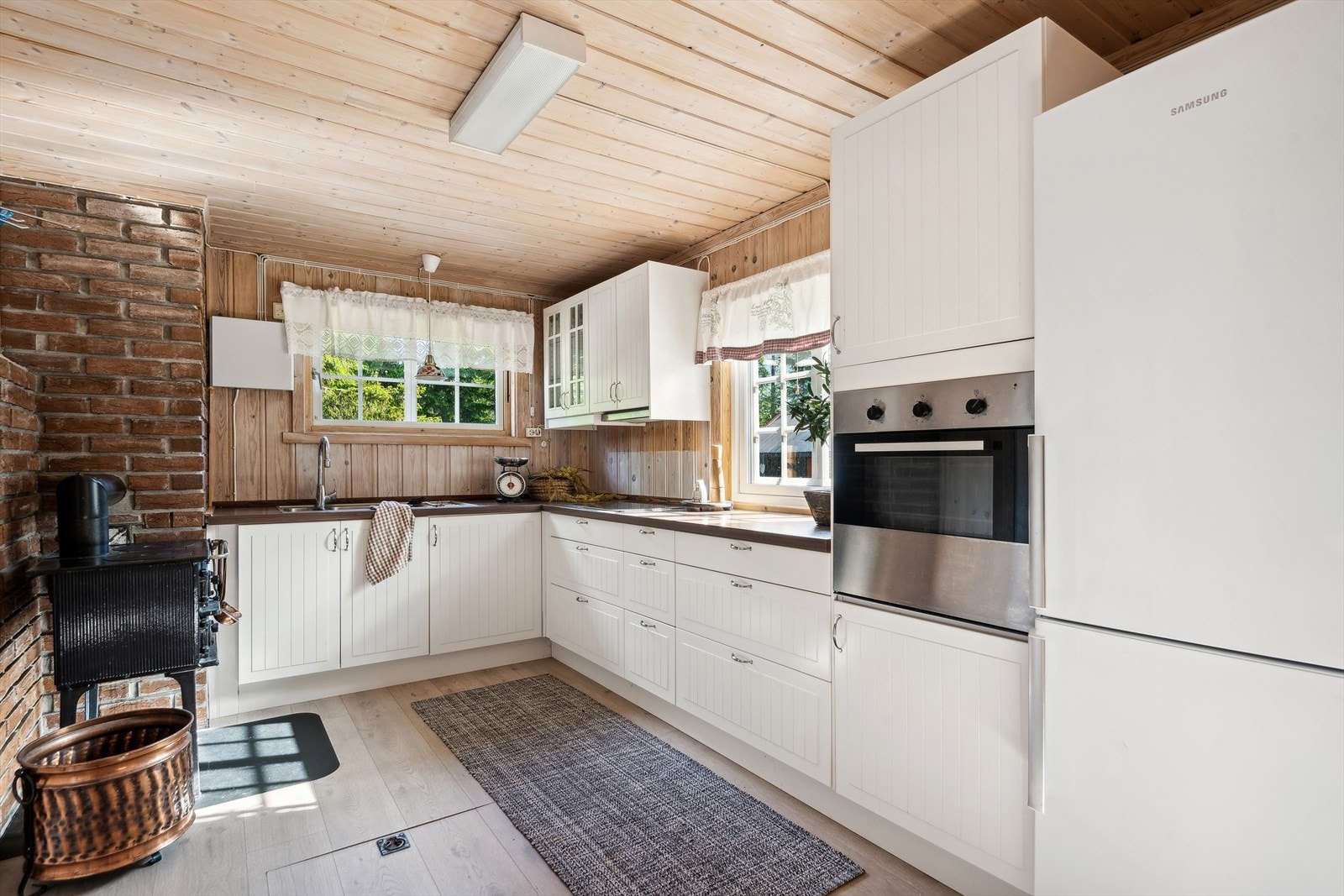 I rommet er det montert IKEA innredning med lyse fronter, hvor ett overskap er med glassdører og laminat benkeplate med nedsenket vask i stål med ett-grepsarmatur. Galleribilde