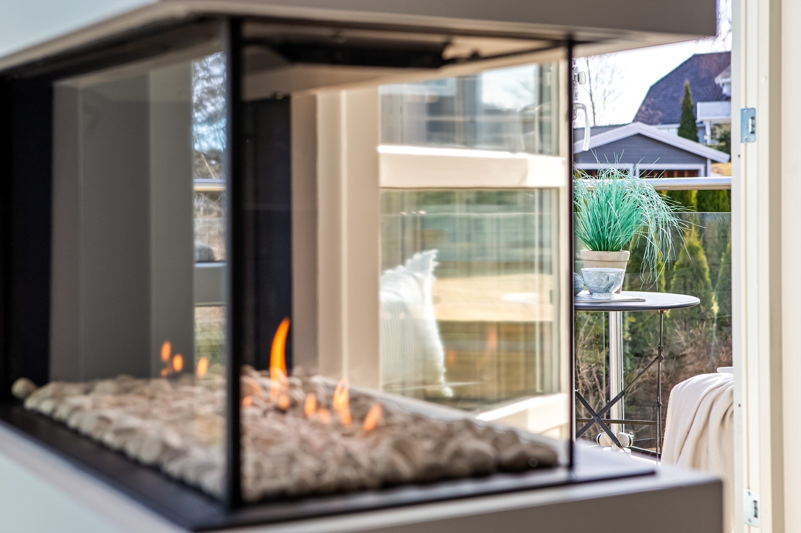 En gasspeis glir sømløst inn og fungerer som romdeler, og stuen har plass til spisebord og sofagruppe på hver sin side av peisen. Galleribilde