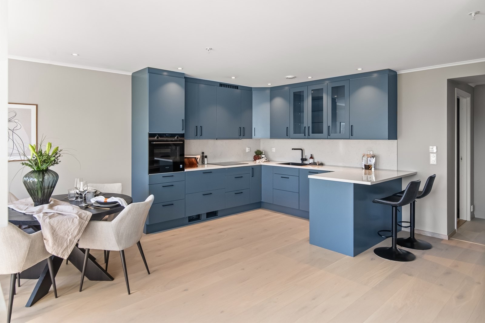 Downlights i taket tilfører ekstra lys til arbeidsflatene. Hvitevarer fra Siemens er integrert, bestående av induksjonstopp, kjøleskuffer, vinskap, oppvaskmaskin og en stekeovn i høyskap. Galleribilde