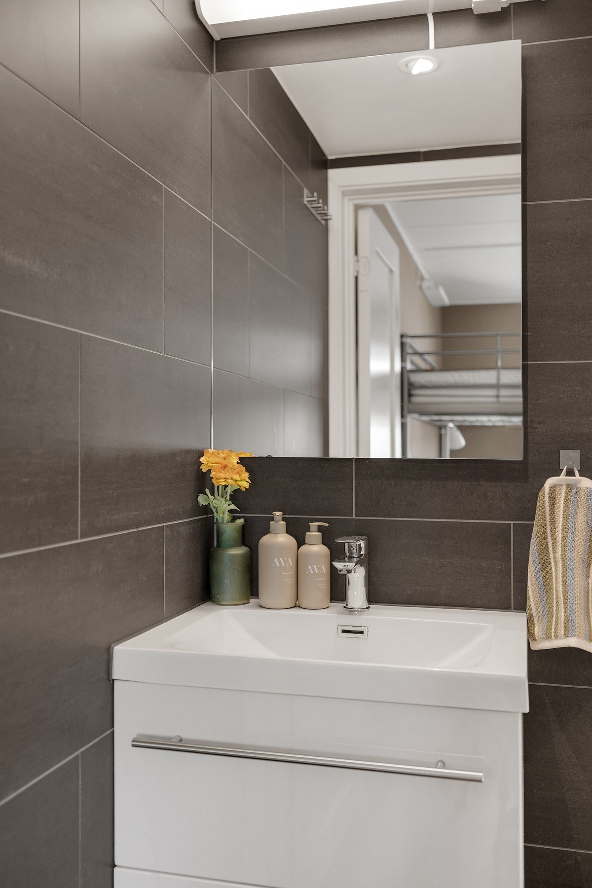 Badet har servantskap, vegghengt toalett, dusjdører i glass og opplegg for vaskemaskin Galleribilde