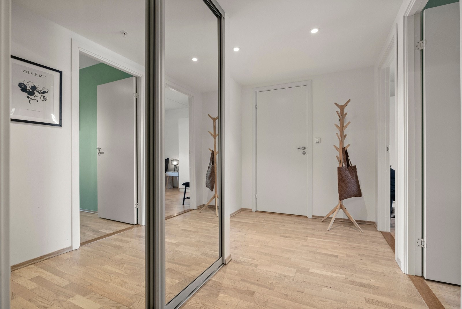 Entréen ønsker deg velkommen med lyse vegger og et stort garderobeskap med speil, noe som skaper en varm og innbydende atmosfære Galleribilde