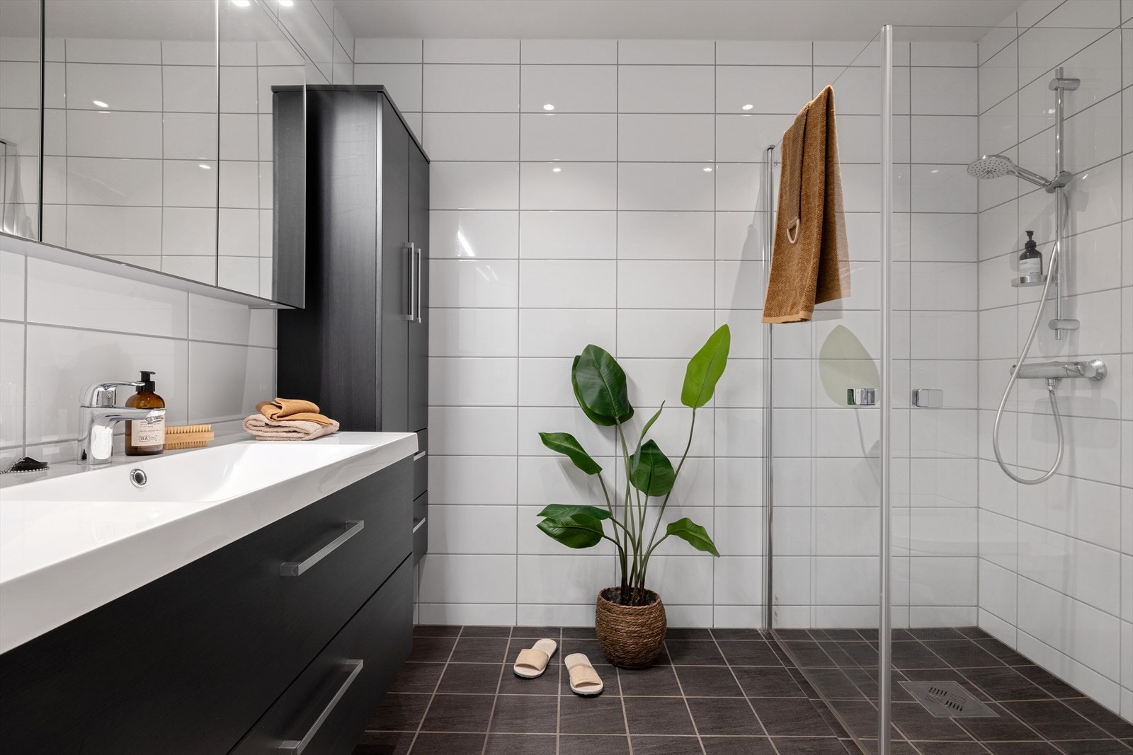 Badet er innredet med servant, veggmontert wc og dusj med dusjdører Galleribilde