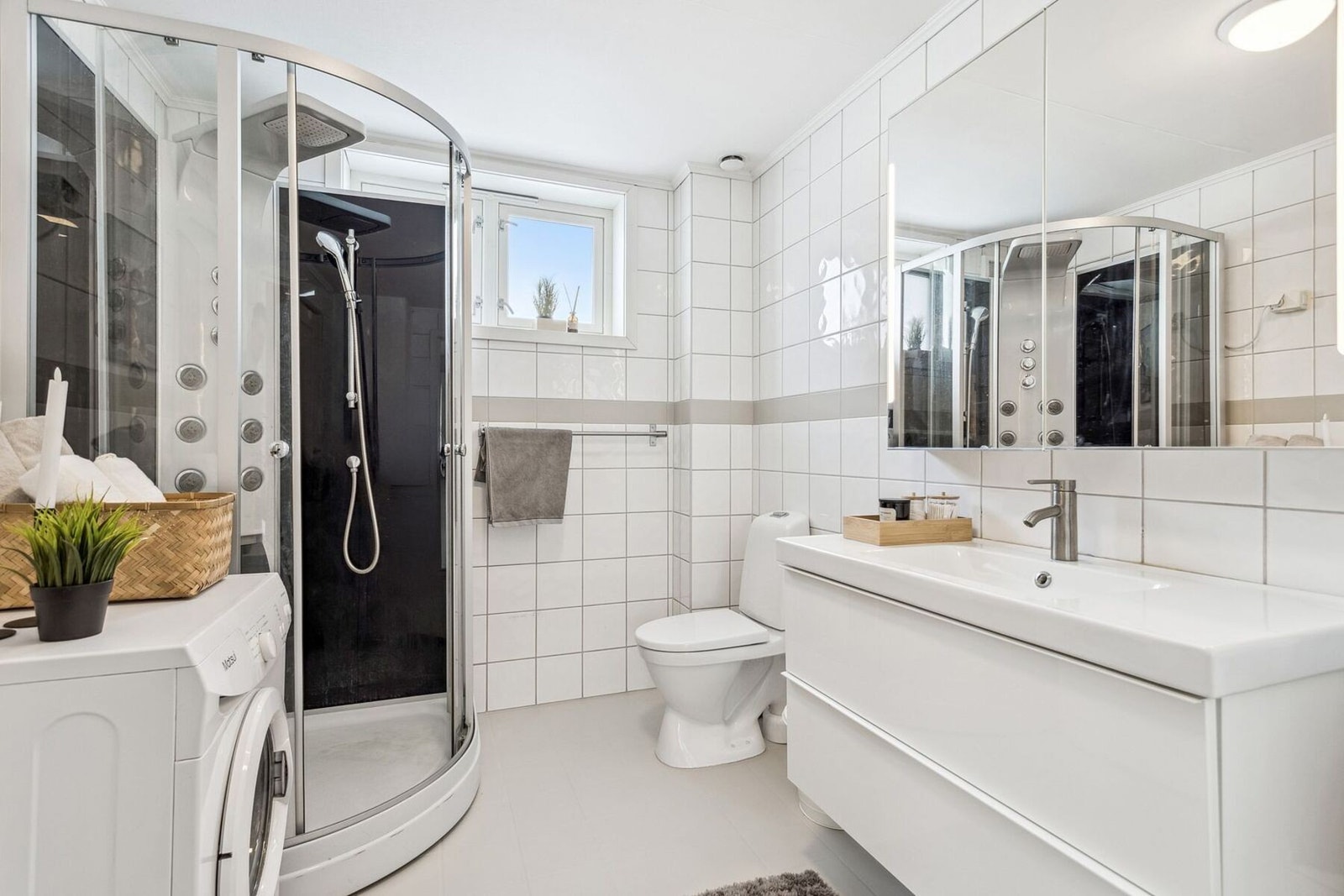 Bad med nyere dusjkabinett, baderomsinnredning og opplegg for vaskemaskin. Galleribilde