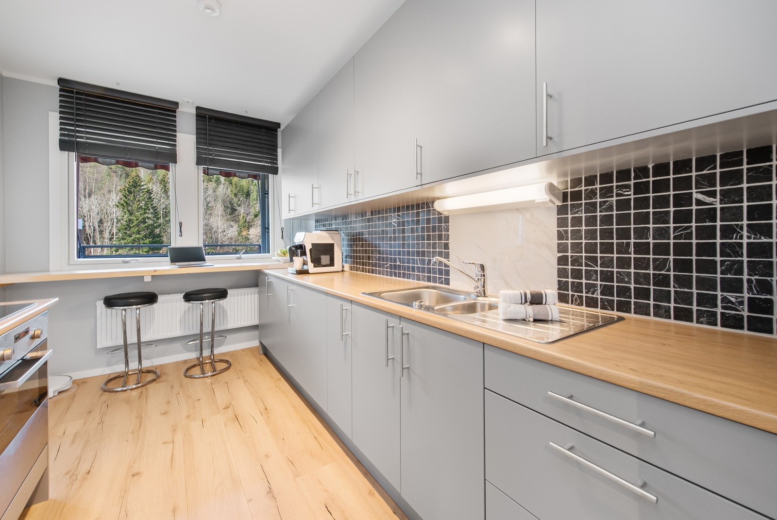 Mellom benk og overskap er det montert svarte fliser som skaper en fin kontrast. Galleribilde