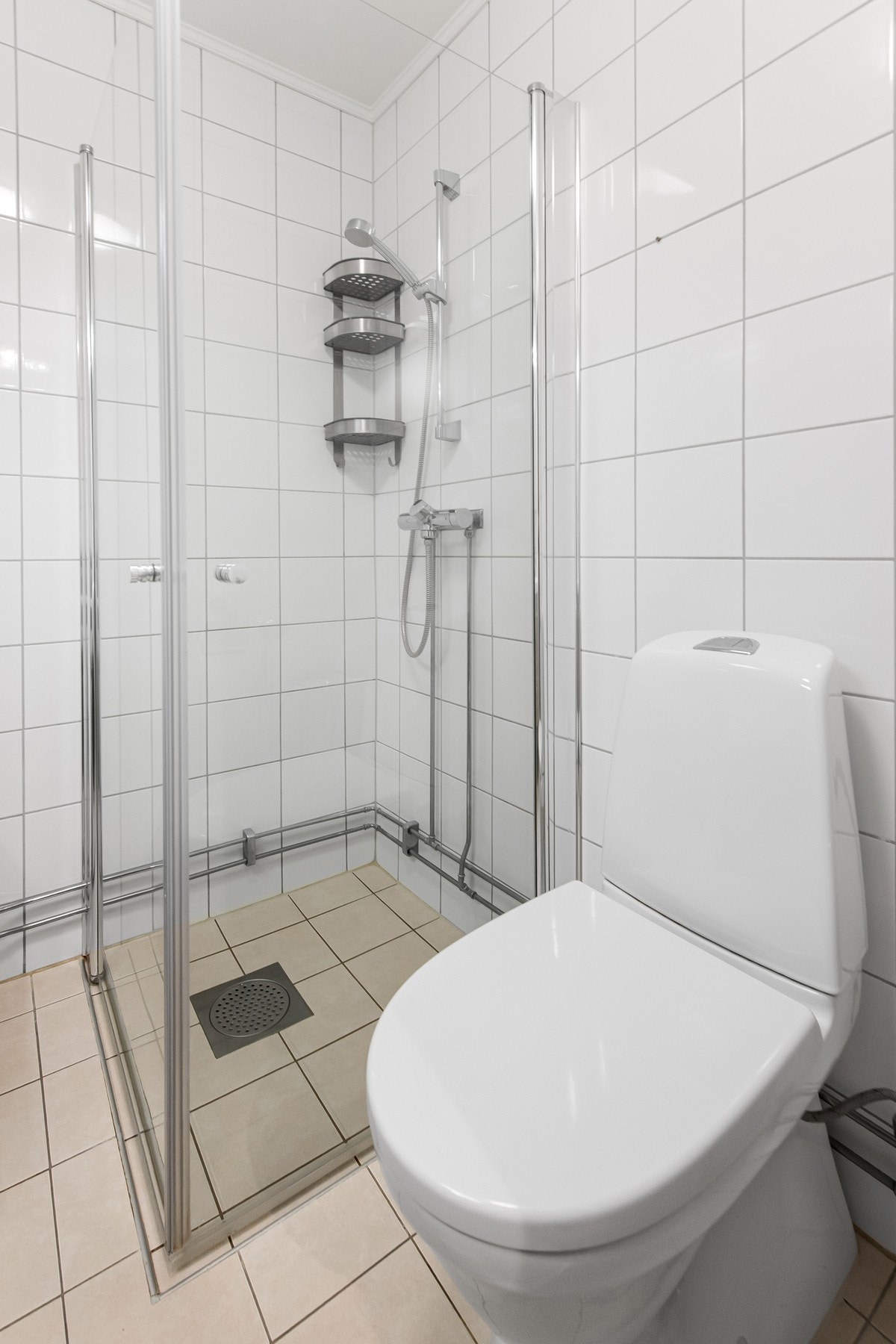 Dusjhjørne med glassdører, gulvstående toalett og opplegg for vaskemaskin. Mekanisk avtrekk sikrer god ventilasjon. Galleribilde