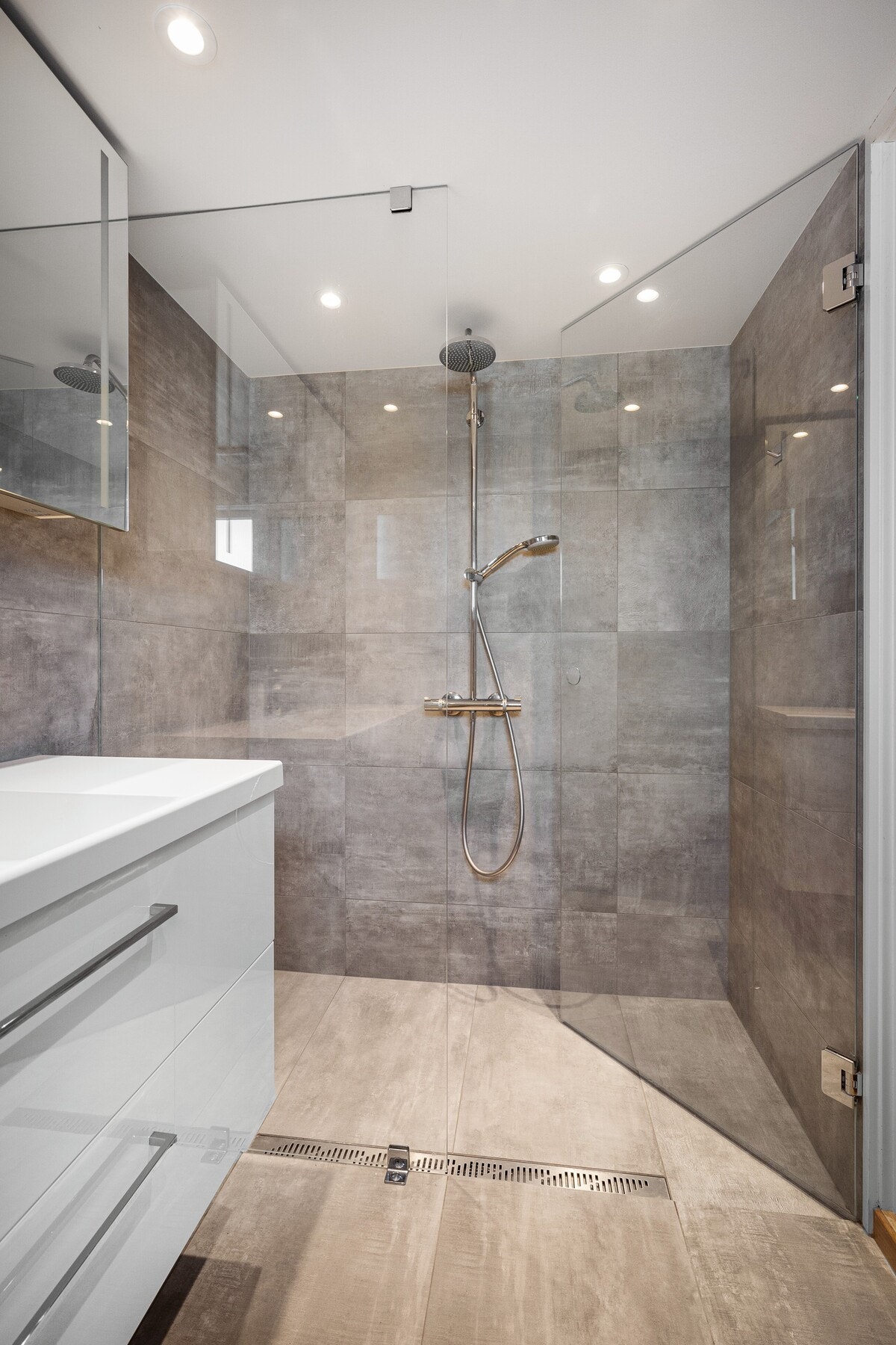 Badet er utstyrt med en romslig dusjsone som gir god komfort. Rommet har flislagte overflater og et nøytralt uttrykk som gjør det både praktisk og lett å vedlikeholde. Galleribilde
