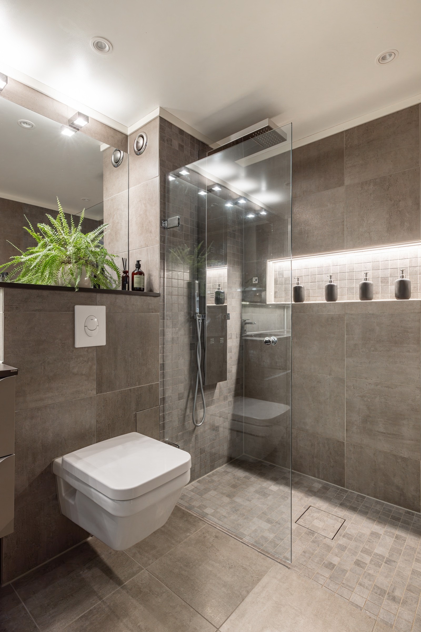 Romslig dusjsone med innfellbare glassdør og armatur med flere dyser, regnfallsdusj og hånddusj. I dusjen er det også en flott innebygd hylle for såper og integrert belysning. Galleribilde