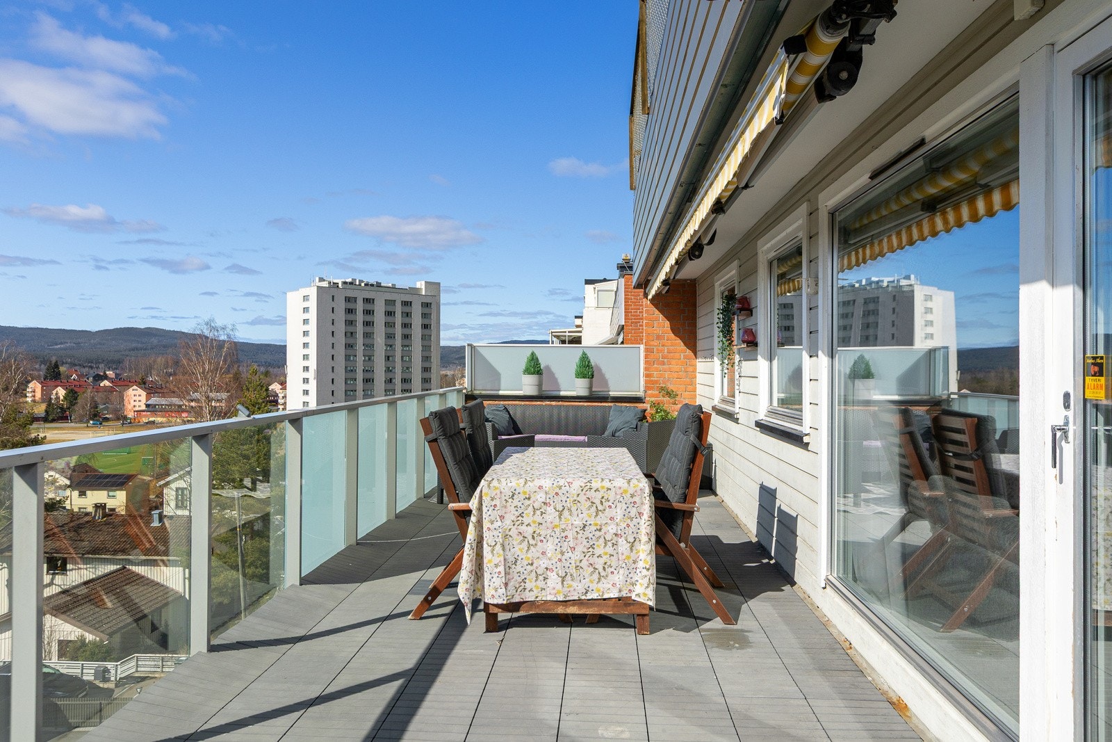 Verandaen er belagt med stilige tremmer/gulvplater, og det moderne rekkverket i metall med glassfronter gir et åpent og elegant uttrykk. Galleribilde