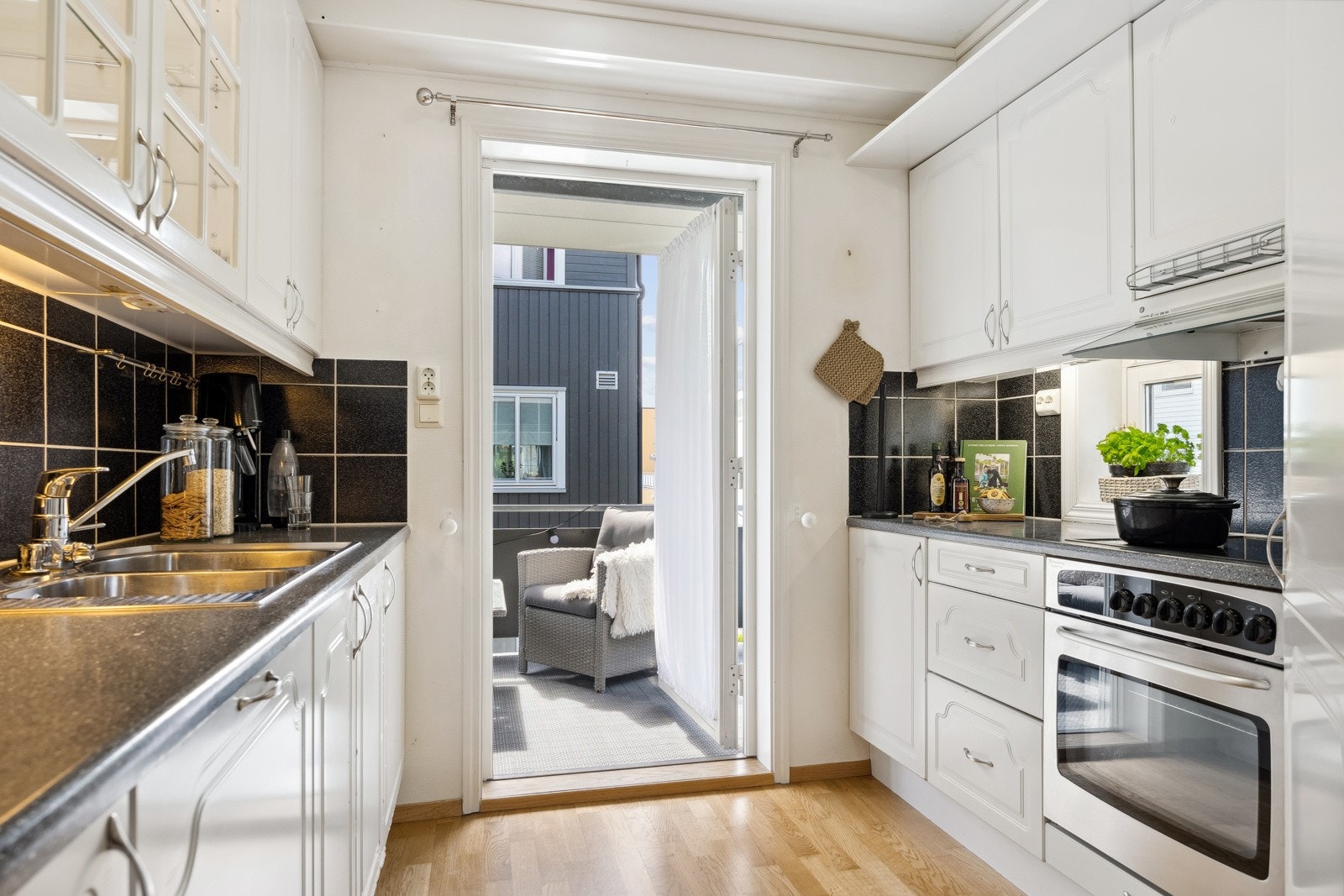 Kjøkkenet er i hvite fronter med mørk benkeplate. Her har man stekeovn, platetopp, oppvaskmaskin og et praktisk hjørnekjøleskap. Galleribilde