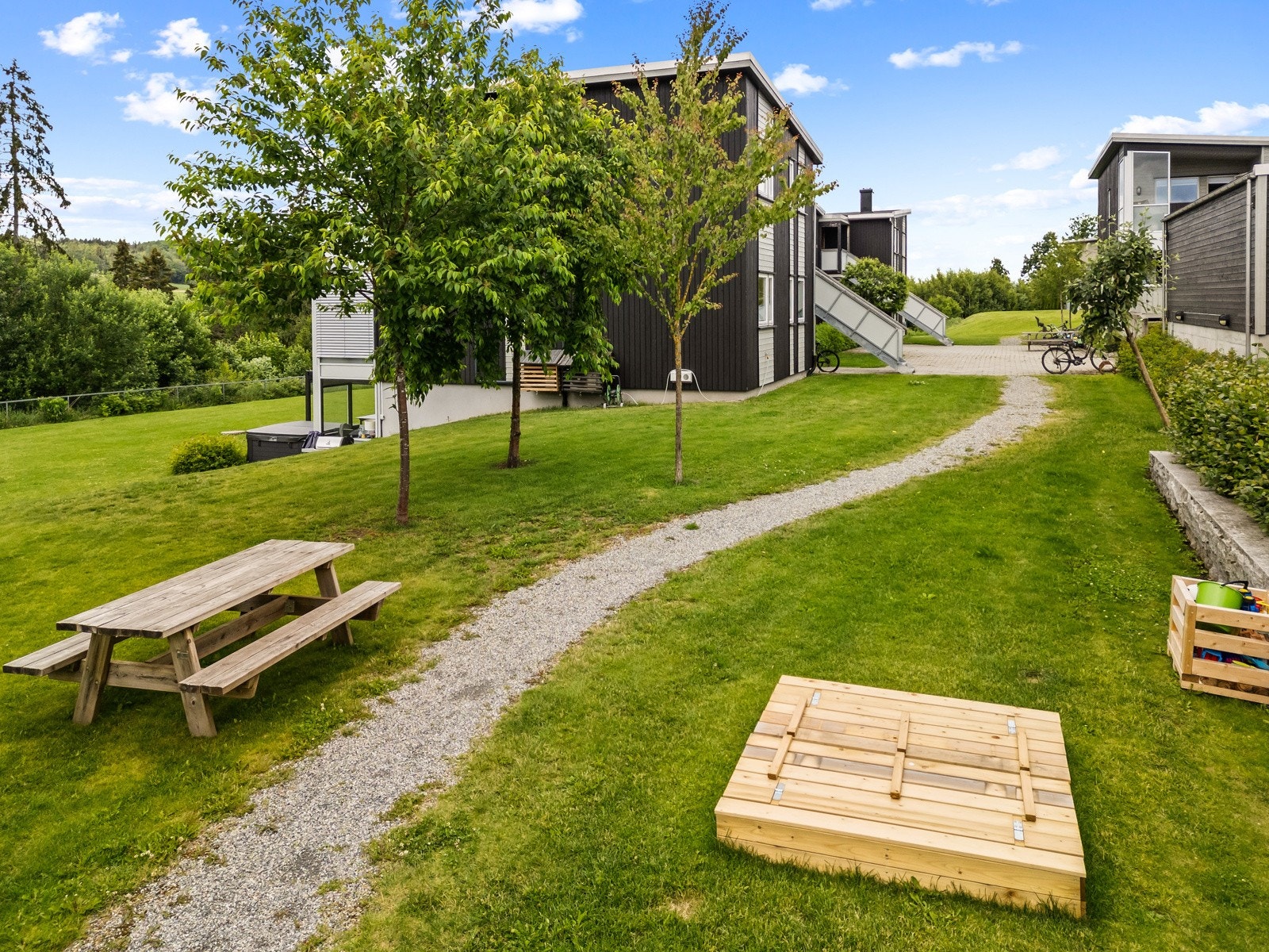 Hyggelige fellesarealer opparbeidet med gressplen og beplantninger, sittegrupper og lekeplass. Galleribilde