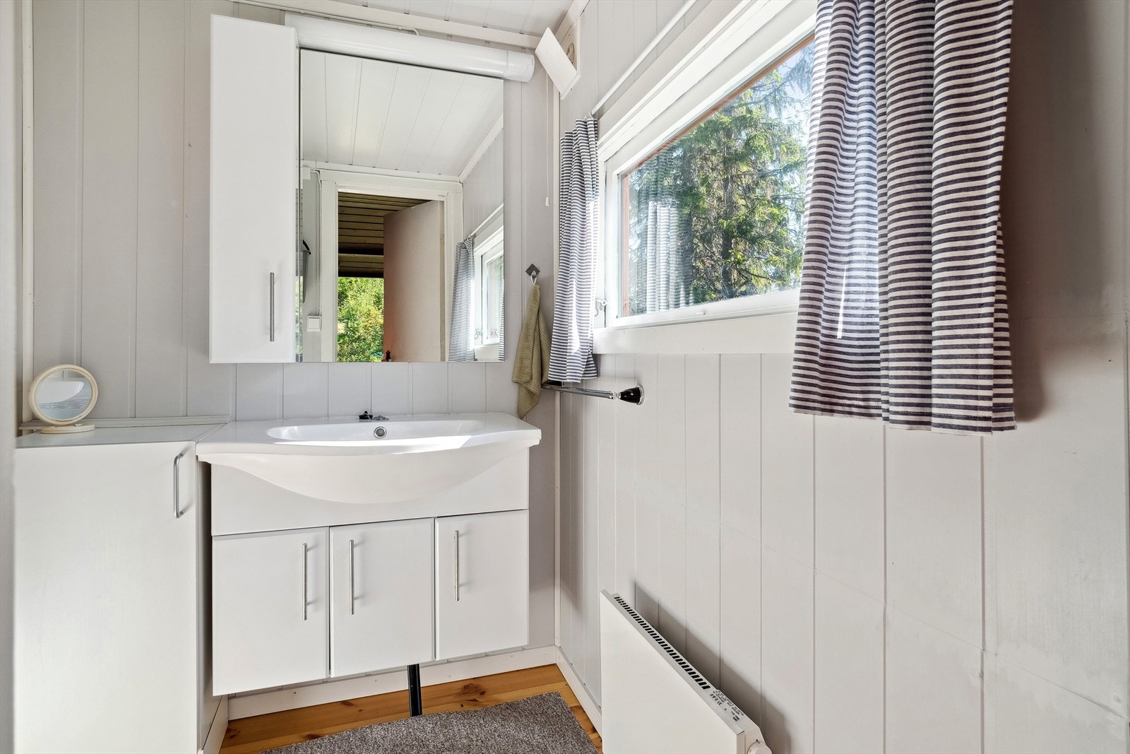 Baderom er utstyrt med vegghengt innredning med skap og overhengt skap og speil. Galleribilde