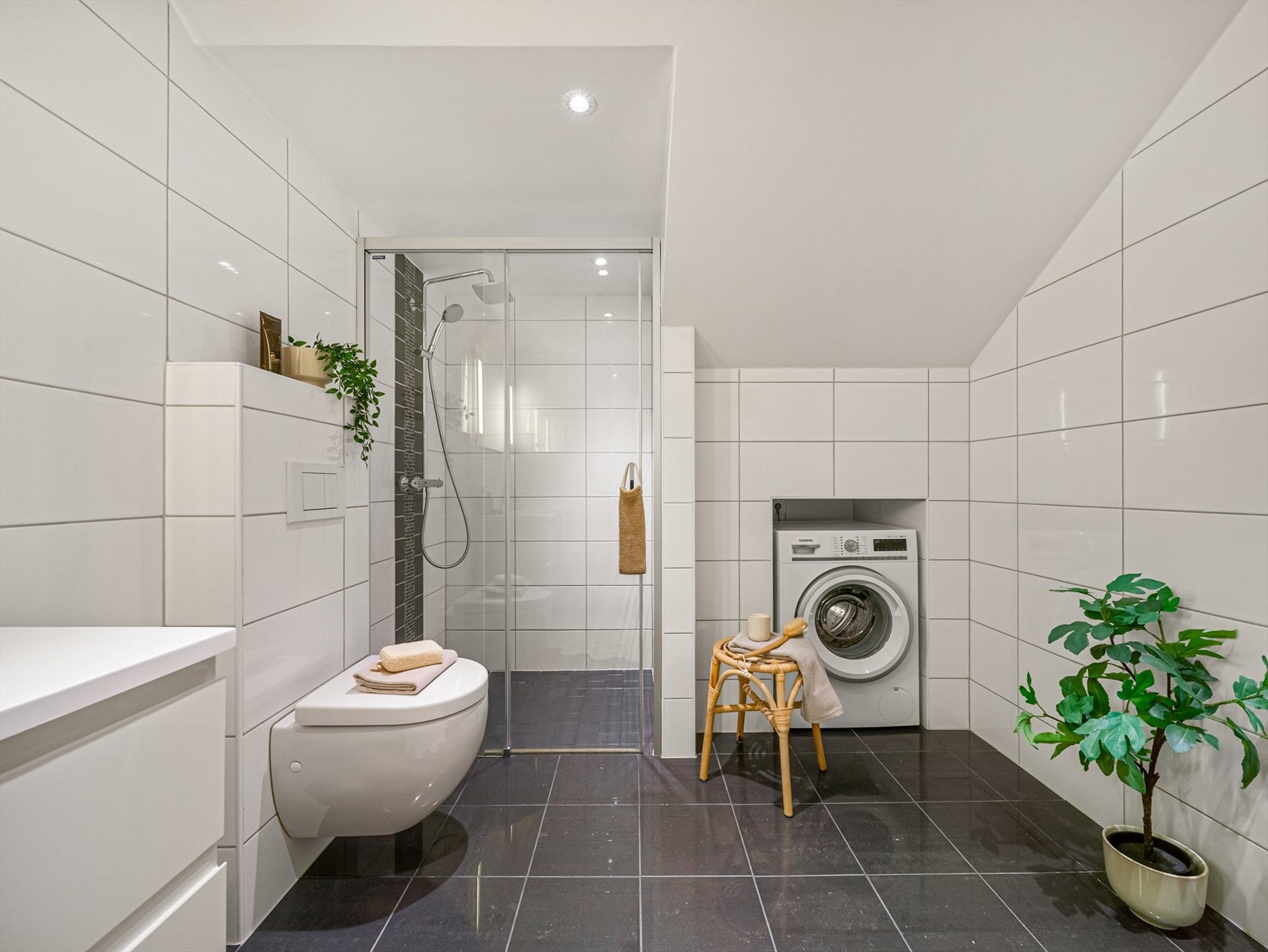 Badet er romslig og praktisk innredet med stor dusjsone og egen nisje for vaskemaskin Galleribilde