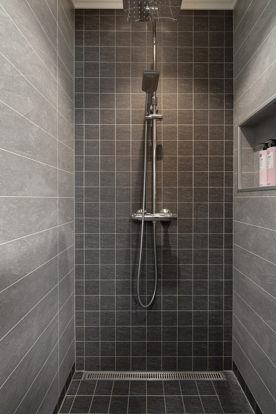 Badet er utstyrt med vegghengt toalett, dusjhjørne, innredning med nedfelt servant og spegel. Galleribilde