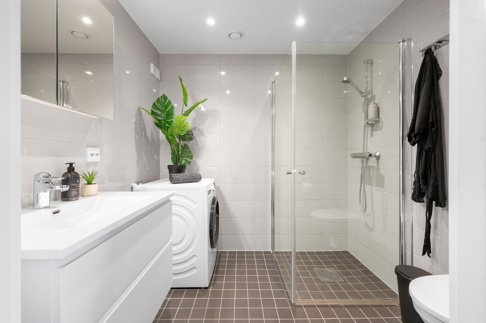 Lekkert, fliselagt bad med god plass - stor dusj, servant med praktisk underskap og plass til både vaskemaskin og tørketrommel. Galleribilde