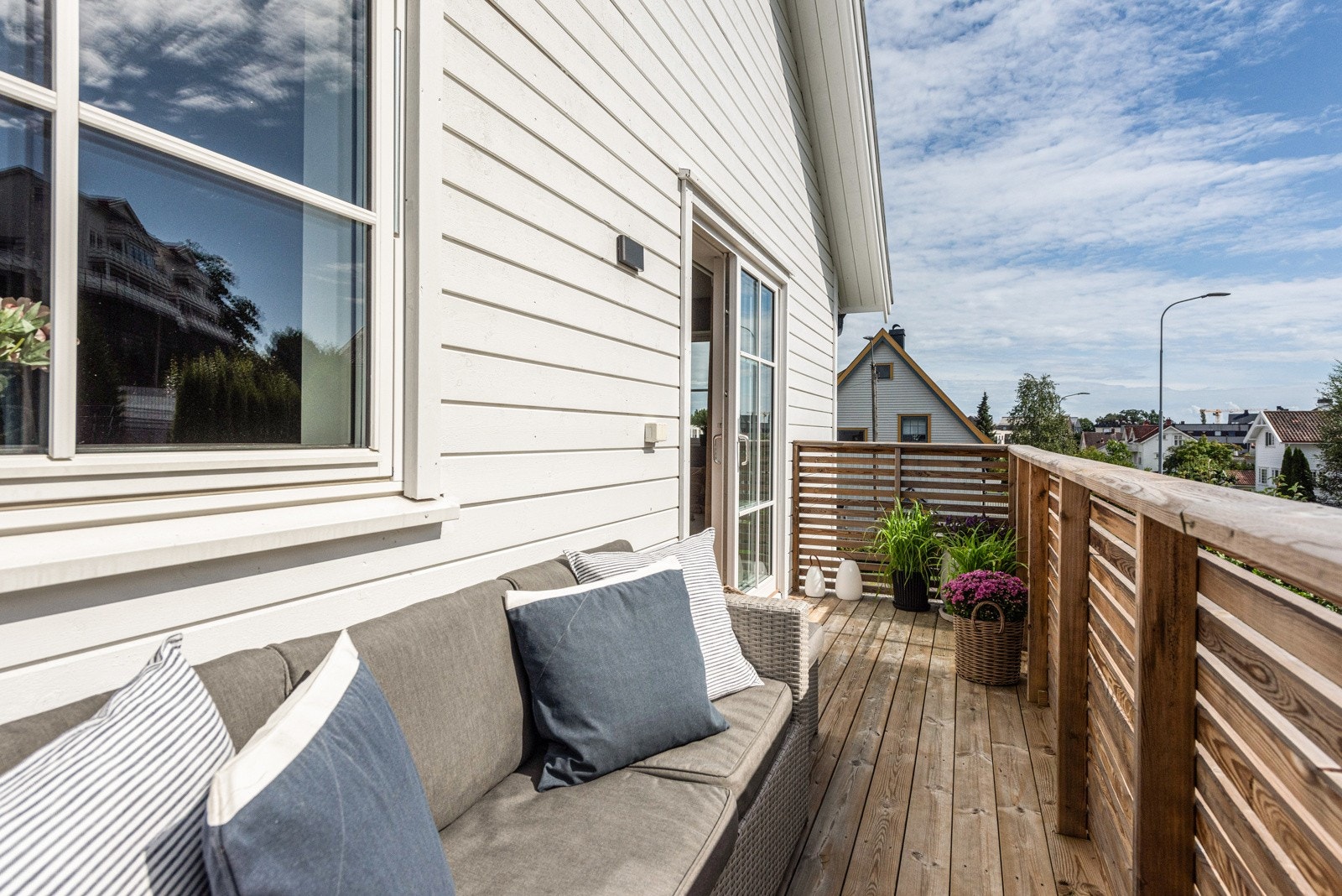 Balkongen har dekke av terrassebord, rekkverk med liggende trespiller og fin plass til møbler, både til utendørs hygge og måltider i solen. Galleribilde