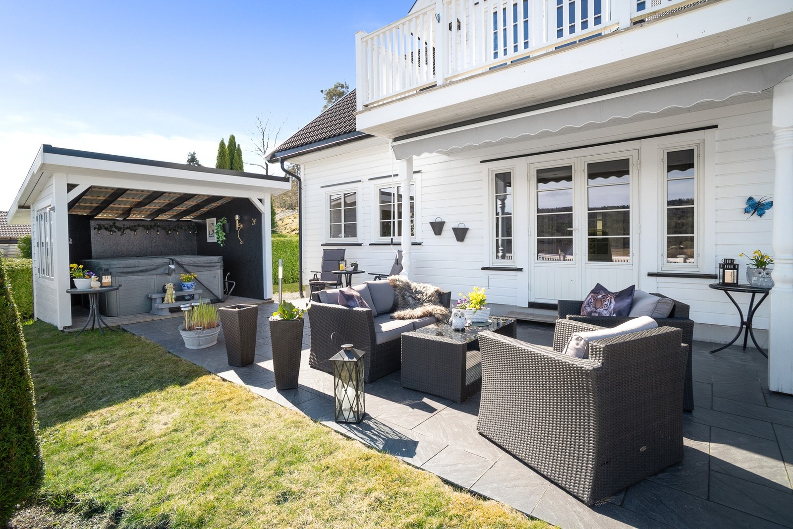 Flott opparbeidet uteområde med grøntareal, flislagt terrasse og overbygd jacuzzi. Galleribilde