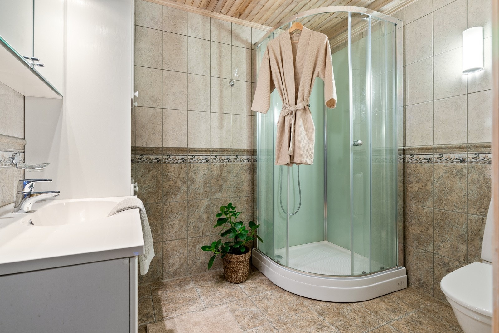 Badet i sokkeletasjen er flislagt med behagelig gulvvarme. Øvrig innredning består av dusjkabinett, toalett og en pen innredning med mye oppbevaringsplass. Galleribilde