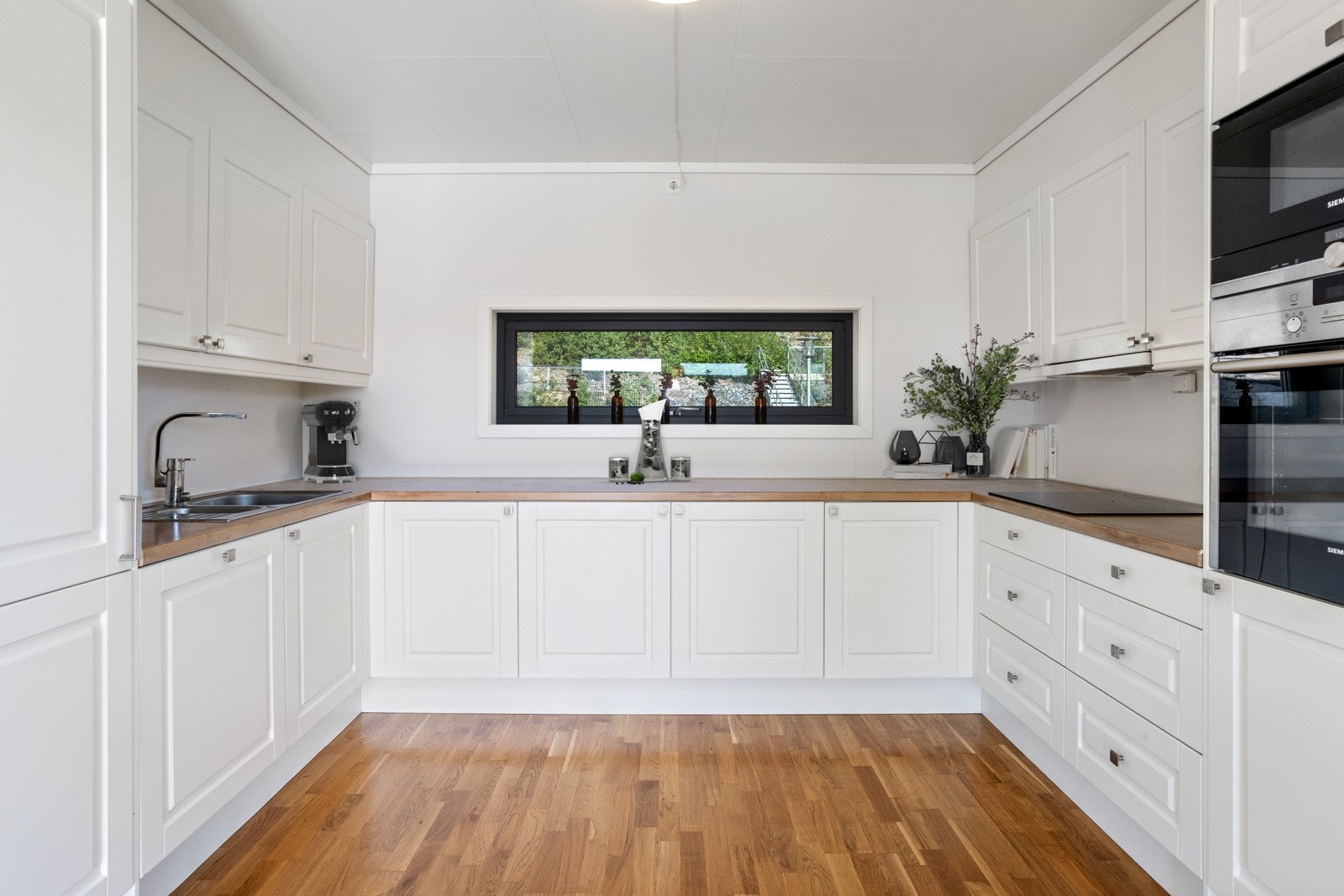 Lekkert kjøkken med profilerte fronter, integrerte hvitevarer og godt med skap- og benkeplass. Legg merke til vinduet som slipper lyset inn. Galleribilde