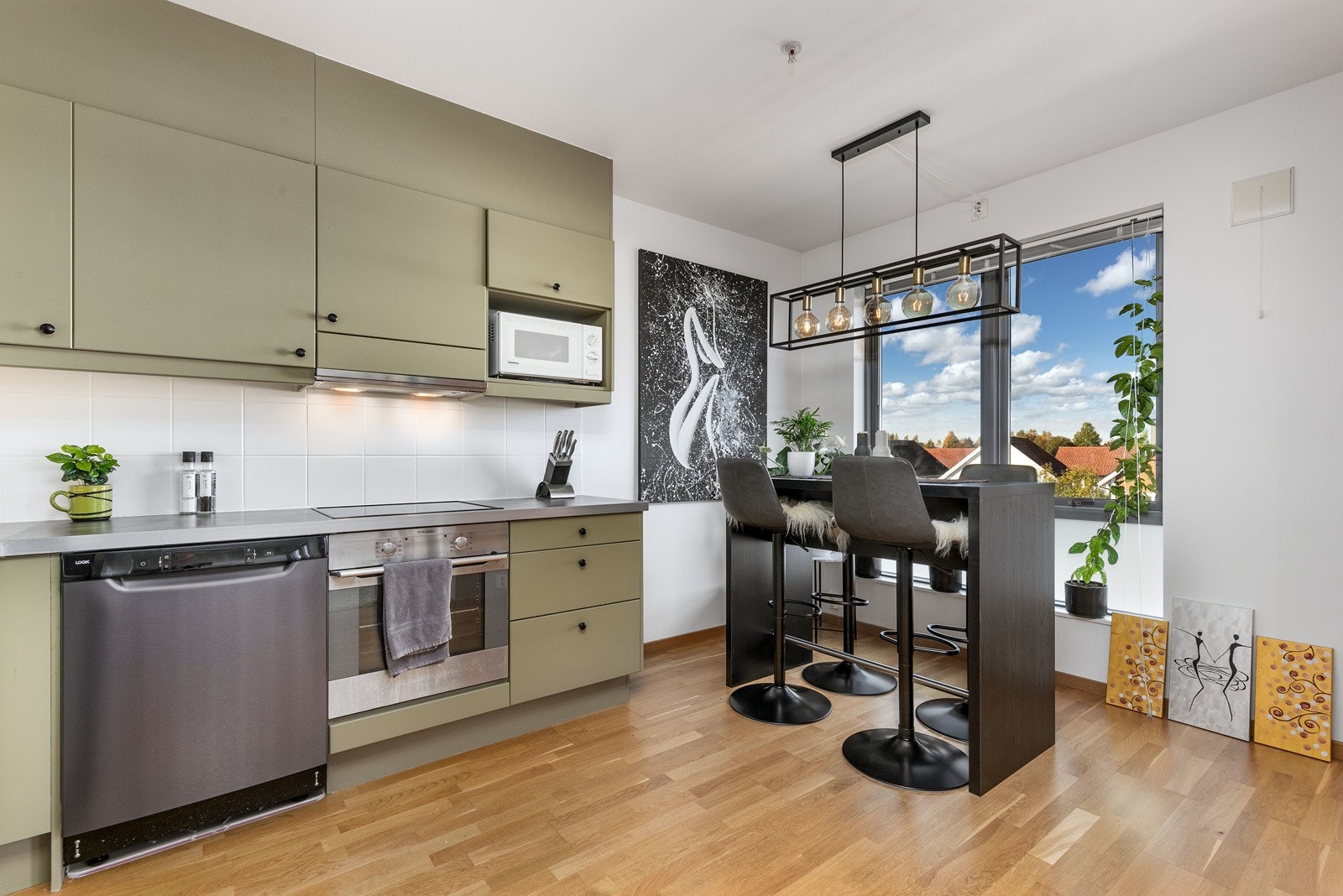 Stilrent vinkelkjøkken i åpen løsning. Kjøkkeninnredning fra byggeår som består av glatte fronter med foring opp til tak og laminert benkeplate med nedfelt oppvaskkum i rustfritt stål. Galleribilde