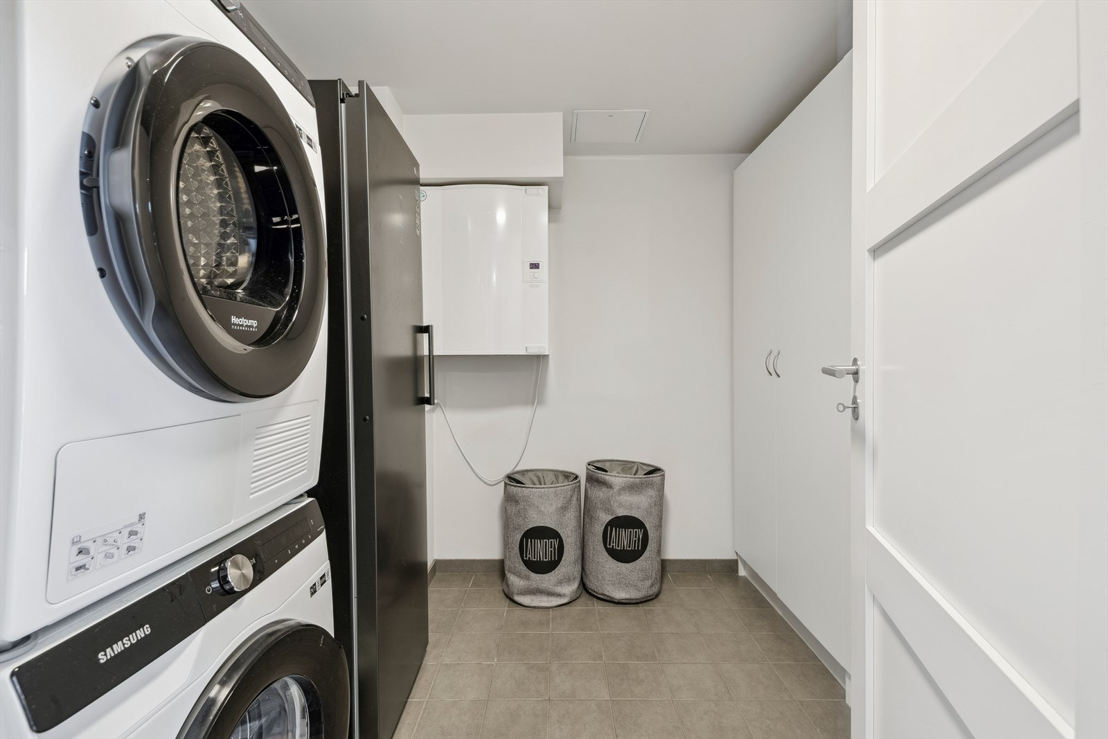 Romslig vaskerom med plass til vaskemaskin og tørketrommel samt praktisk oppbevaringsplass. Galleribilde