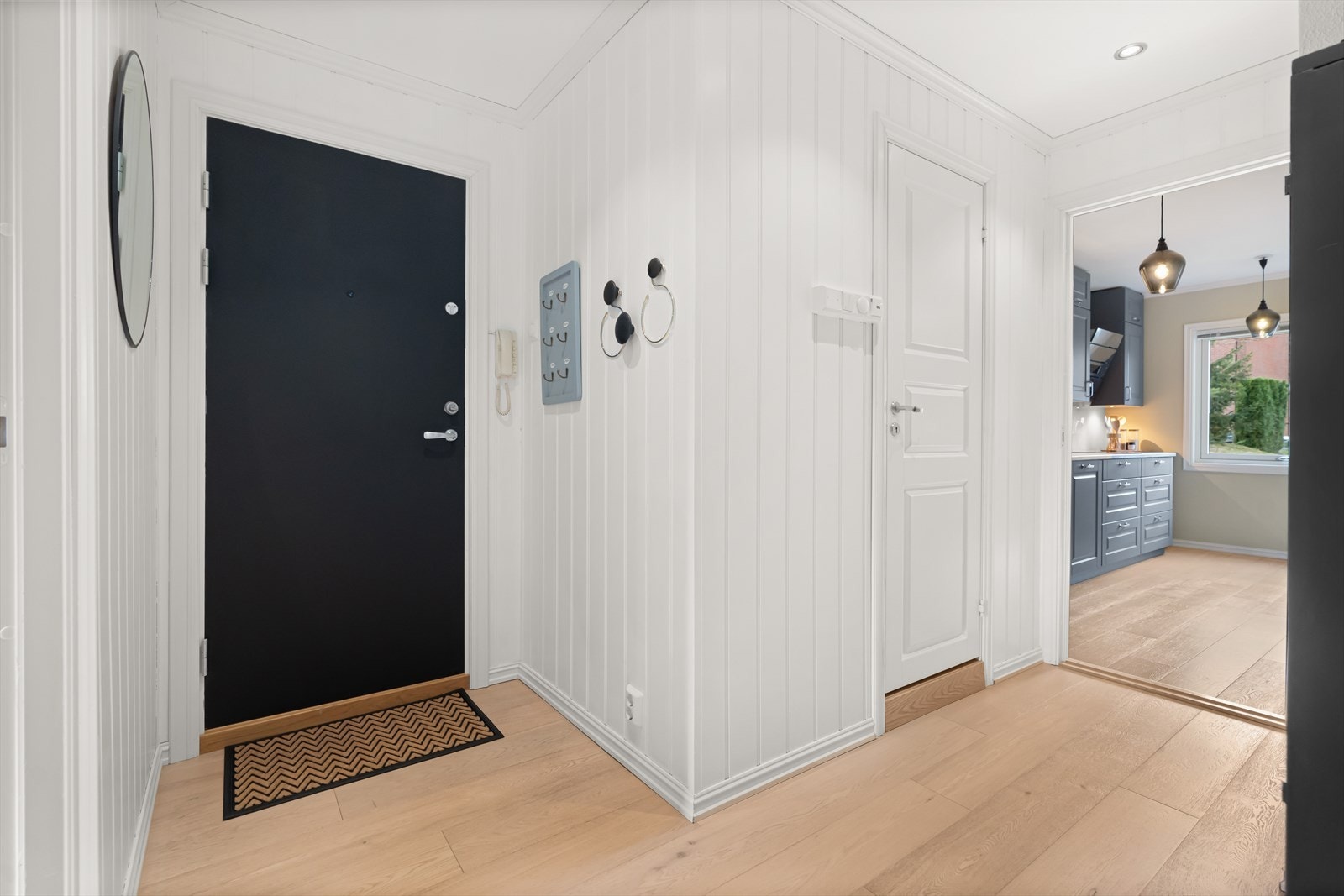 Leiligheten har en innbydende entré med pent parkettgulv og veggpanel malt i lyse toner. Galleribilde