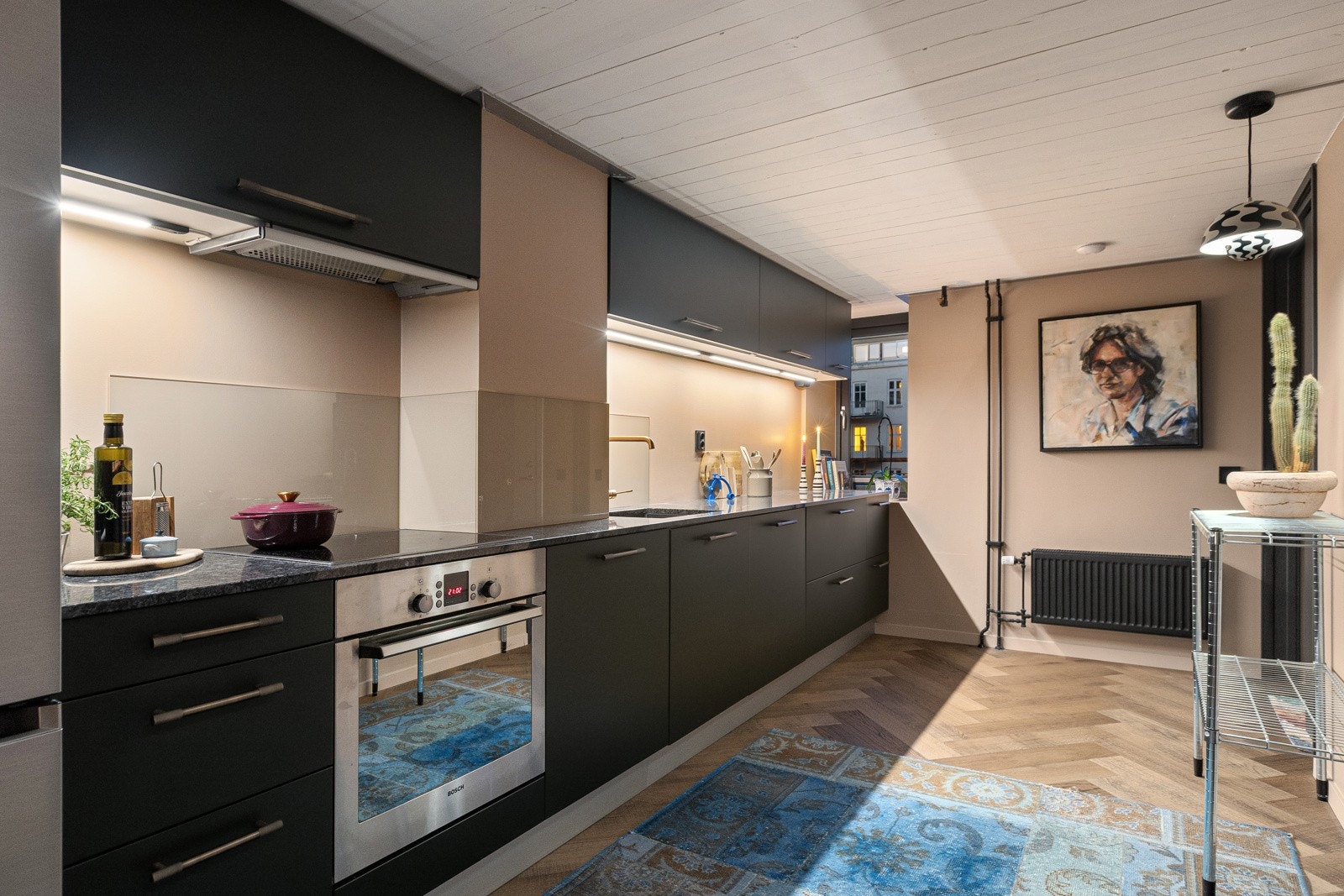 Det er Nerostein benkeplate av granitt med underlimt oppvaskkum og armatur fra Grohe, backsplash over deler av kjøkkenbenk og håndtak fra Lovehandles. Galleribilde