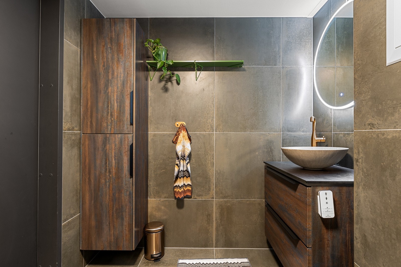 Baderomsinnredningen består av servantskap med skuffer og ovenpåliggende bollevask fra Scala Bad, samt et vegghengt speil med belysning og stikkontakt plassert over servanten. I tillegg er det et høyskap med ekstra rom for oppbevaring. Galleribilde