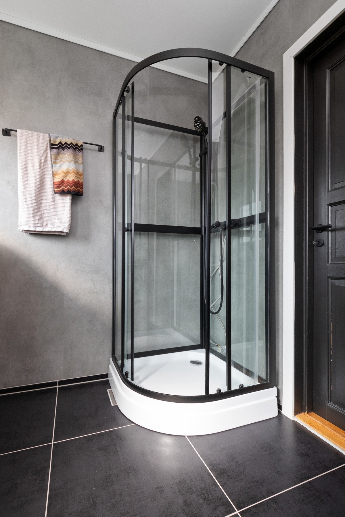 Varmekabler er installert, og badet har toalett og et dusjkabinett med sorte detaljer. Galleribilde