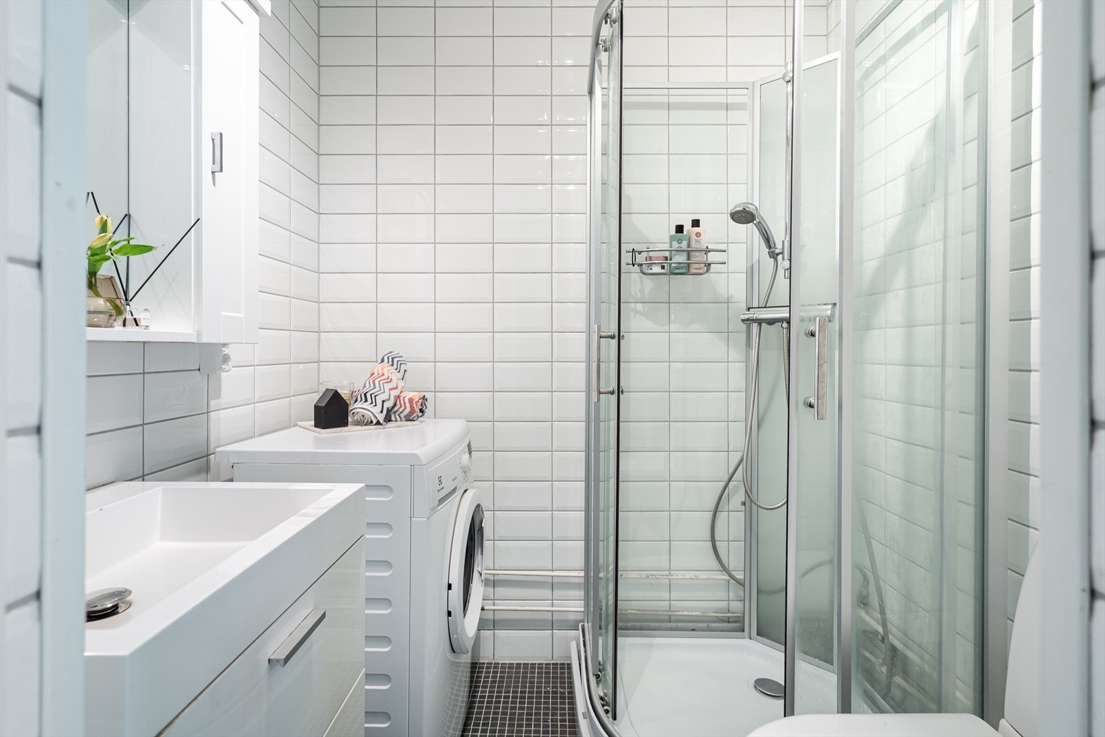 Badet er fra 2009 og har mørke fliser på gulvet, lyse fliser på veggene og opplegg for vaskemaskin. Galleribilde