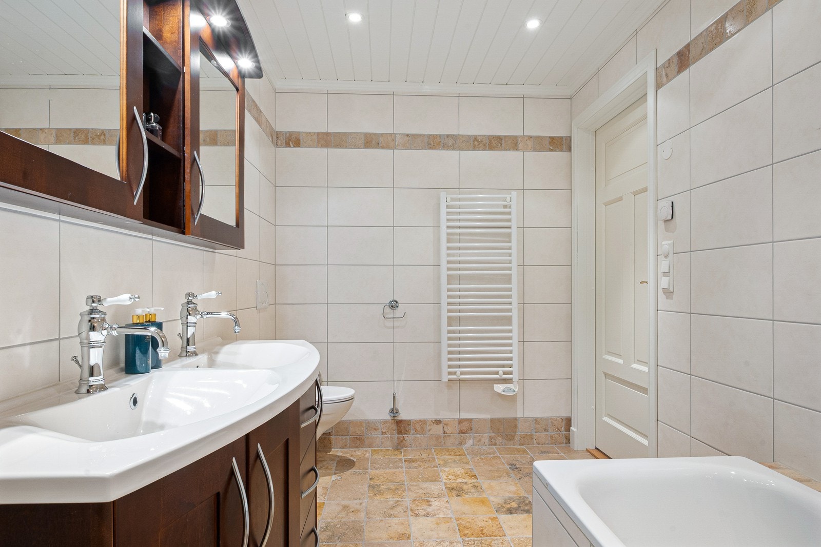 Boligen har et hovedbad og et praktisk kombinert bad og vaskerom, begge plassert i underetasje. Hovedbadet har flislagte overflater, gulvvarme og downlights. Galleribilde