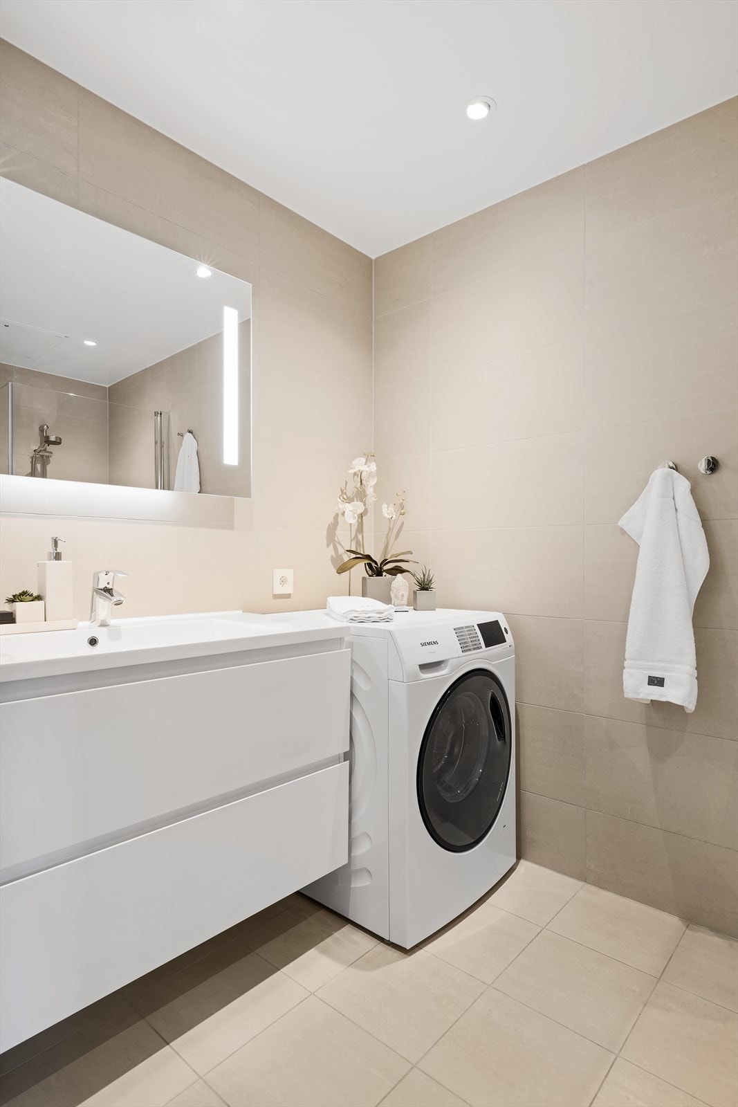 Lekkert flislagt bad med opplegg for vaskemaskin Galleribilde