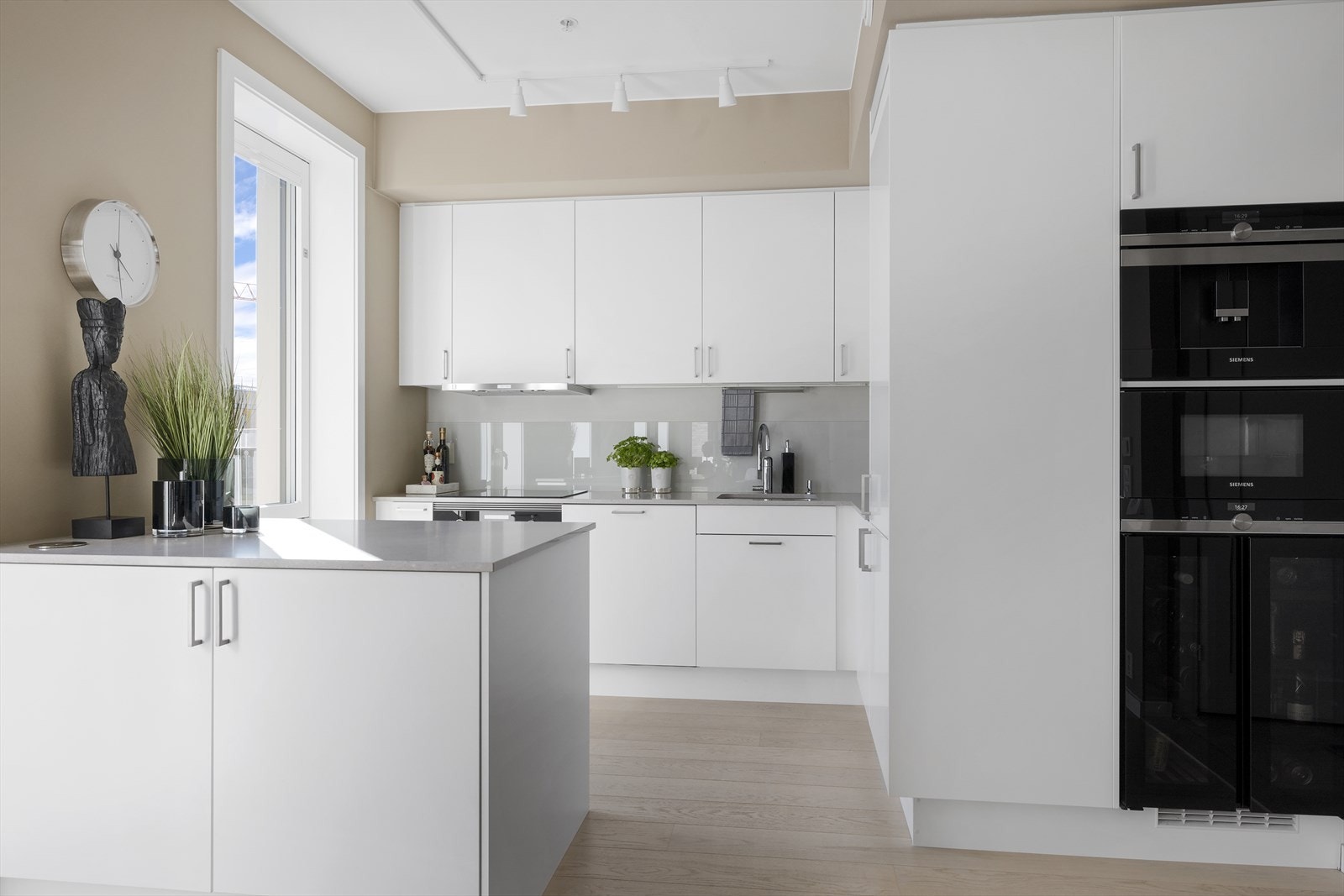 Stilrent kjøkken med alt av moderne hvitevarer som integrert kaffemaskin og vinskap Galleribilde