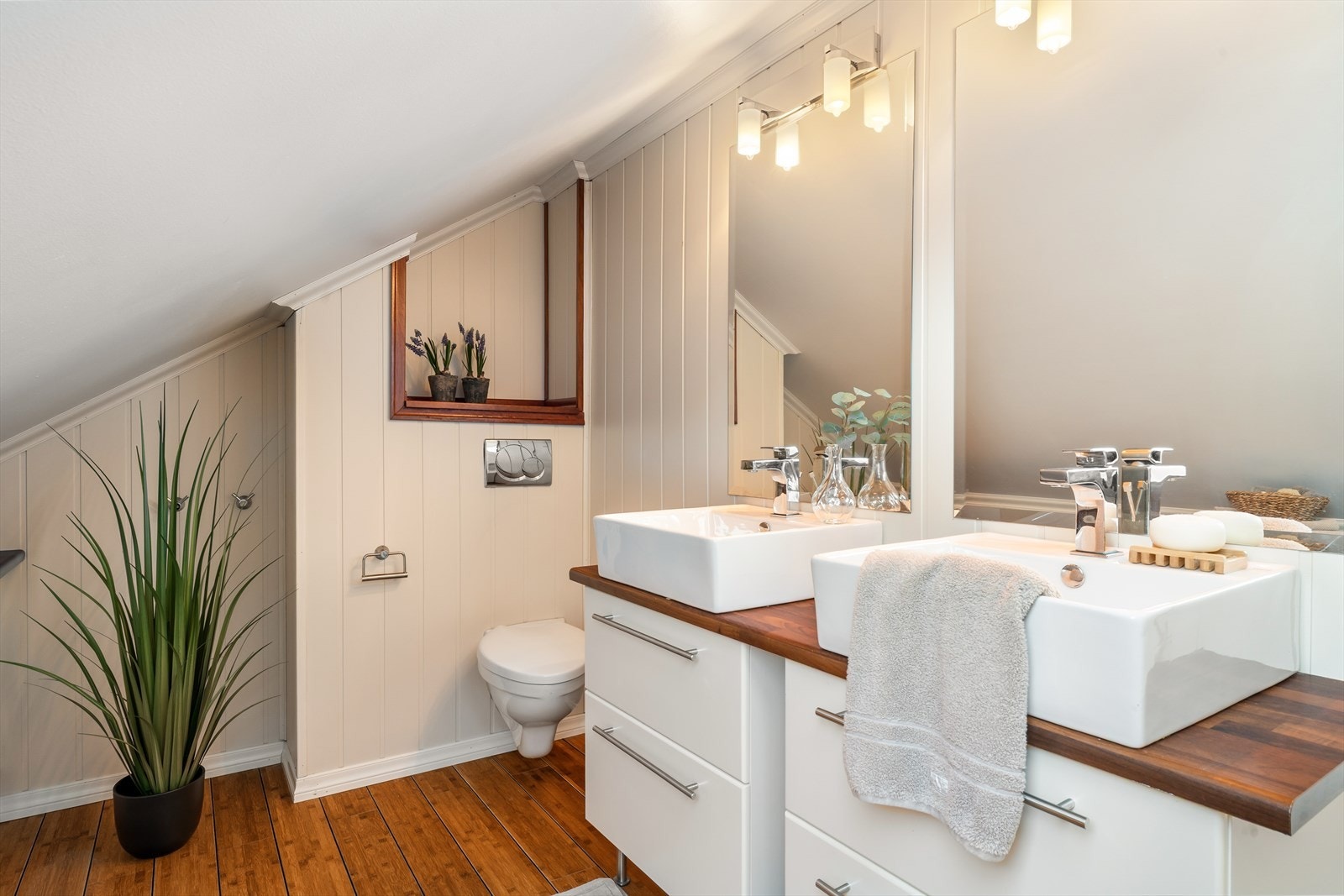 Funksjonelt wc-rom med vegghengt toalett, skap og baderomsmøblement med dobbel servant. Galleribilde