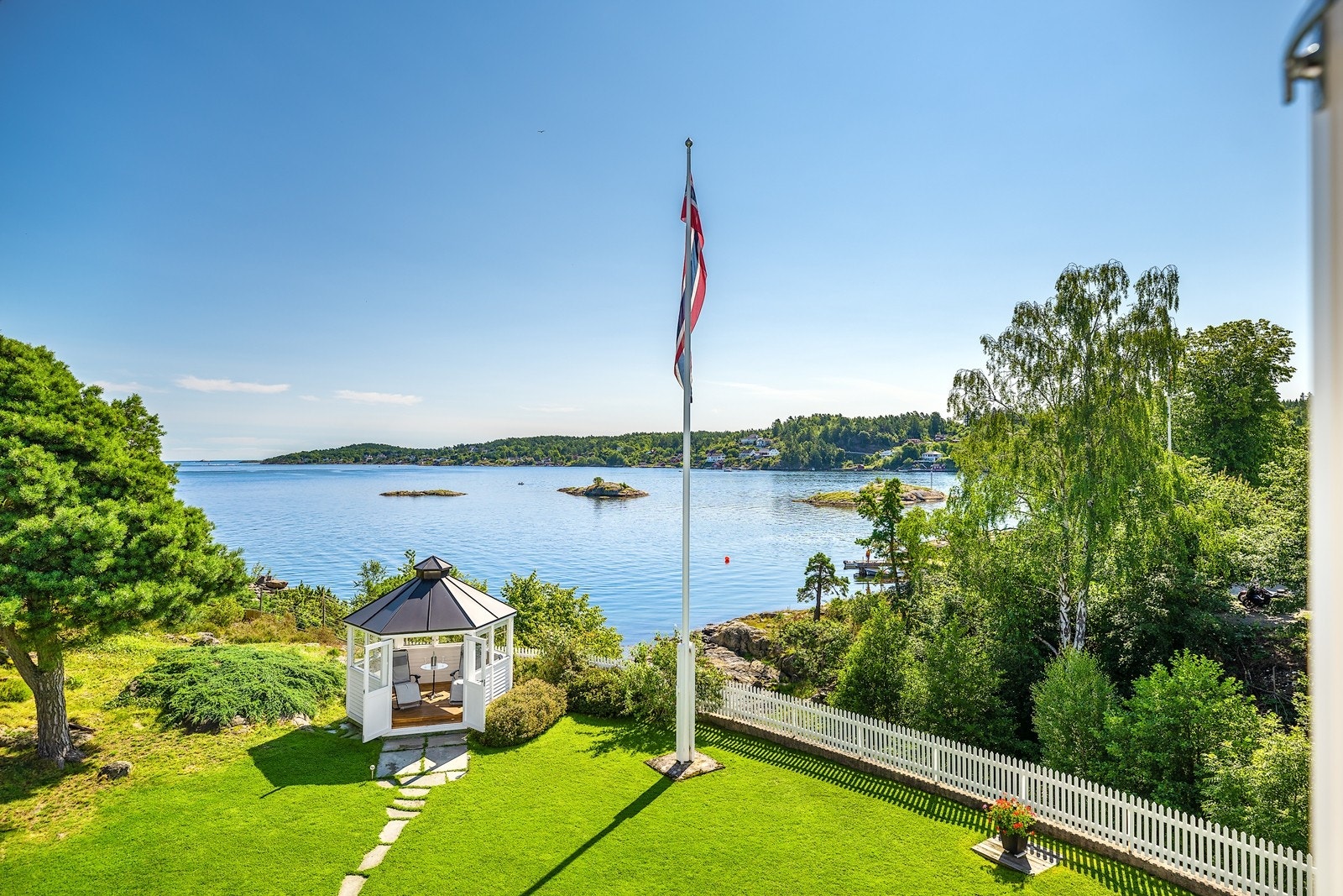 Idyllisk beliggende og omkranset av vakker natur like ved vannkanten. Lysthus plassert i fronten av tomten hvor man får utsikt over det omkringliggende landskapet. Galleribilde