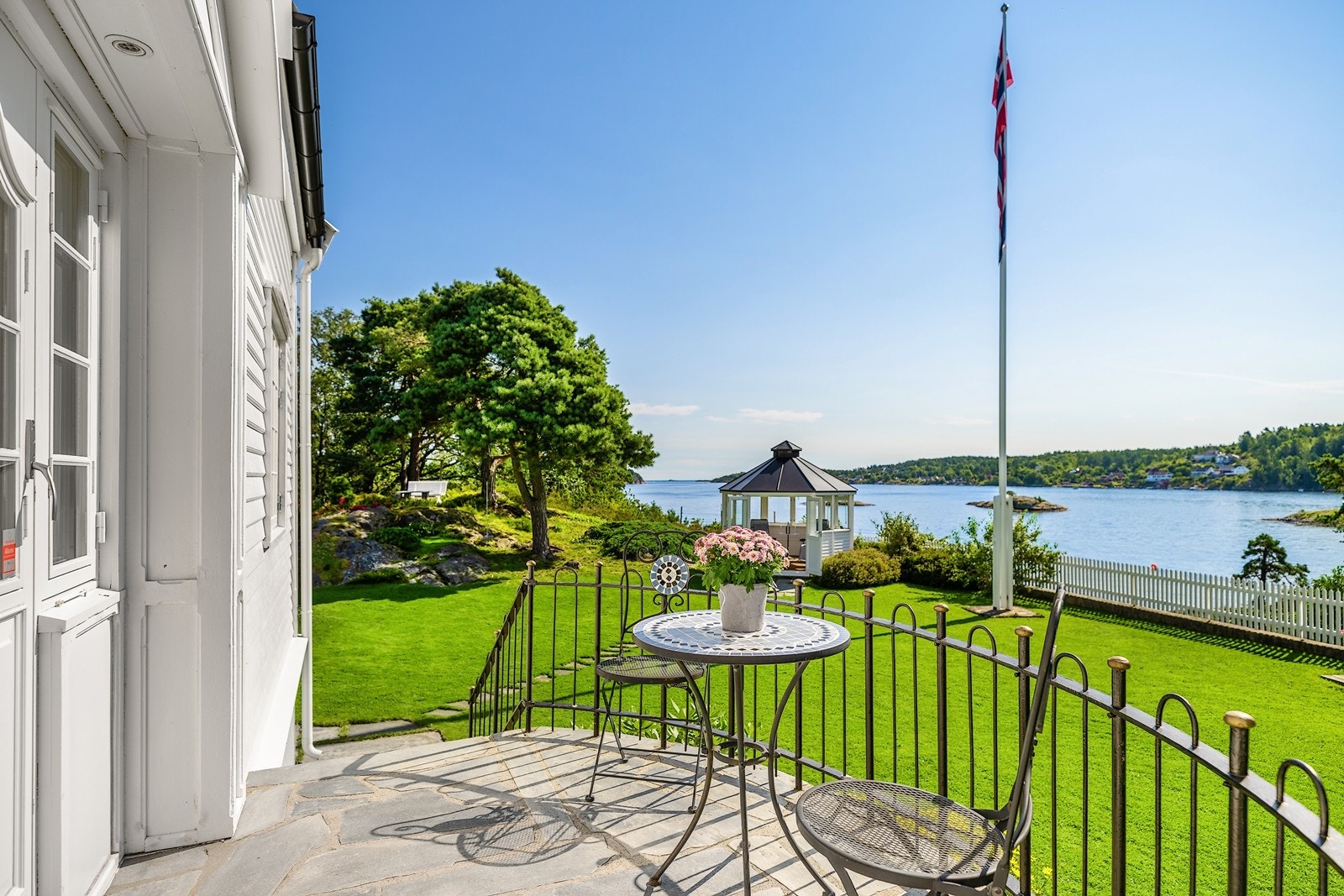 Fra stuen er det utgang til terrasse med skiferstein og smijernsgjerde, og videre ned til hagen som byr på flere soner med sittegrupper Galleribilde