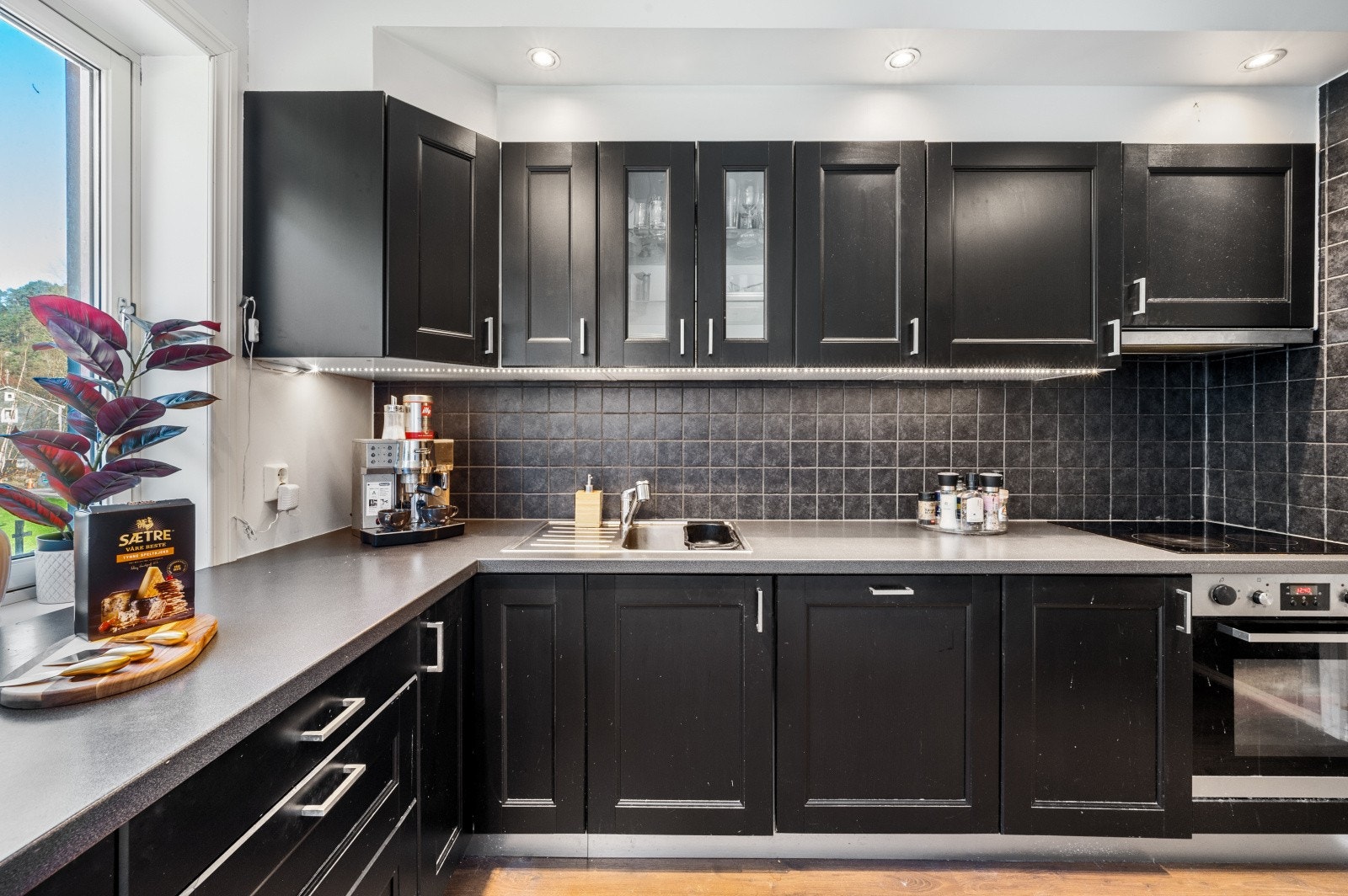 Stilig kjøkkeninnredning med laminert benkeplate og sorte profilerte fronter. Galleribilde