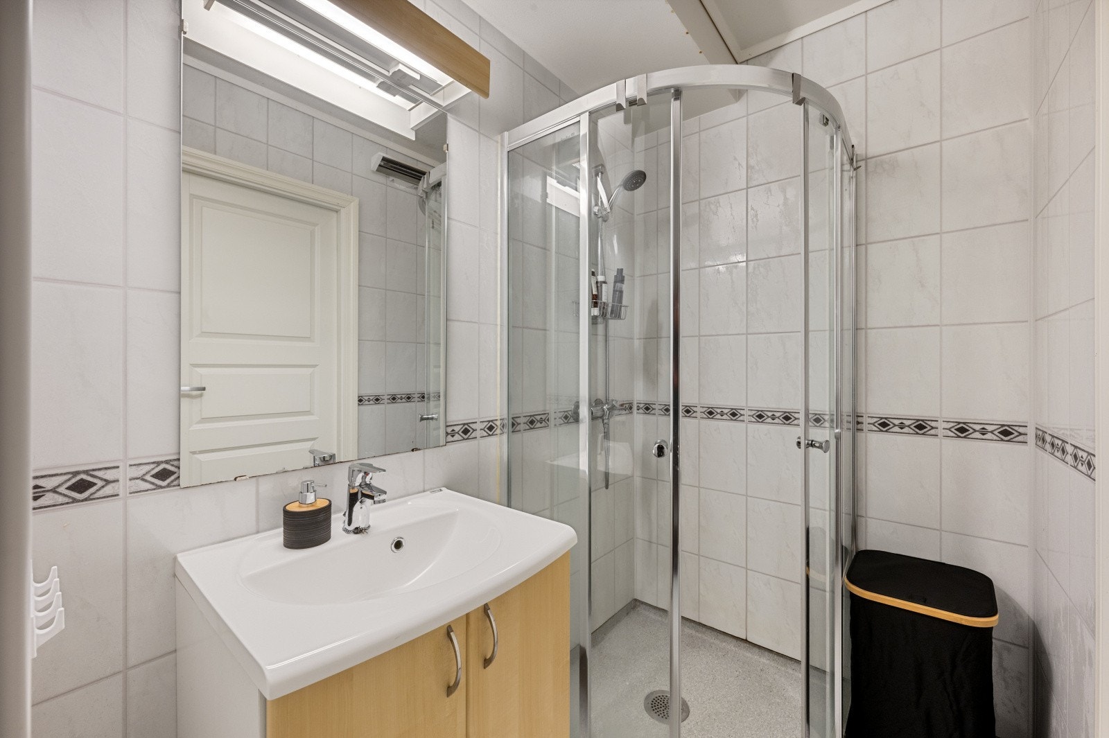 Badet er innredet med dusjhjørne m/glassvegger og servant med innredning, speil og belysning. Galleribilde