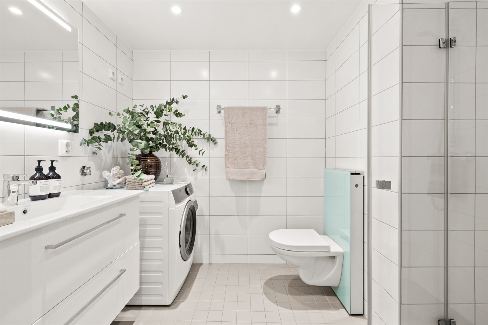 Delikat og lekkert flislagt baderom med gulvvarme og downlights i himlingen. Galleribilde