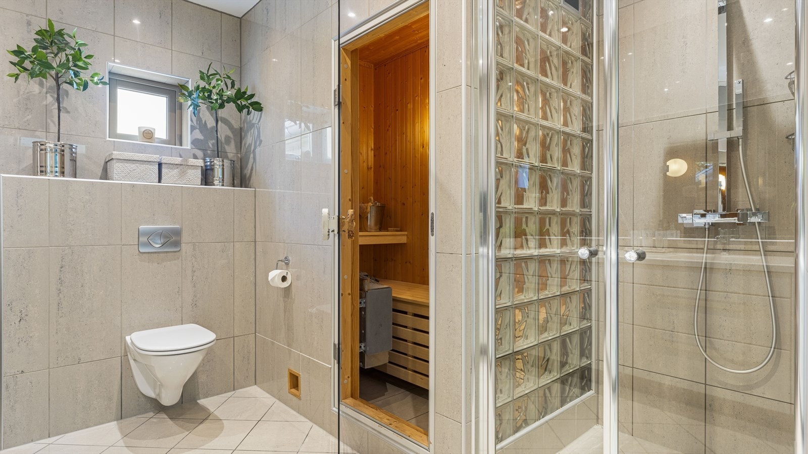 Badet er flislagt med varmekabler, vegghengt toalett og stor dusjsone. Galleribilde