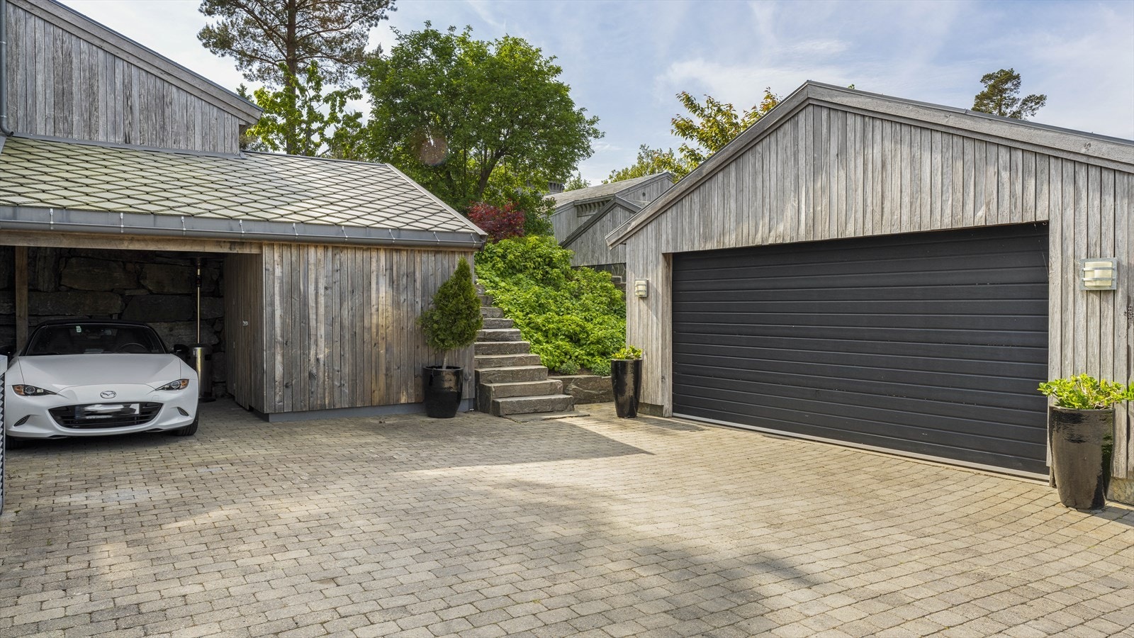 Dobbel garasje med elektrisk port. Legg merke til den særdeles flotte natursteinstrappa som leder opp til hagen. Galleribilde