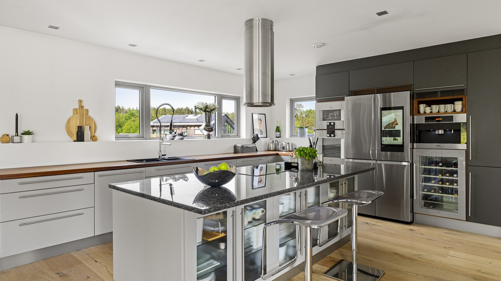 Dette kjøkkenet mangler ingenting. Her er vinskap, kaffemaskin, dobbel kjøl/frys med isbitmaskin og stekeovn/kombidampovn for å nevne noe. Alt integrert i funksjonsvegg. Produktene kommer blant annet fra kvalitetsleverandører som Miele og Gaggenau. Galleribilde