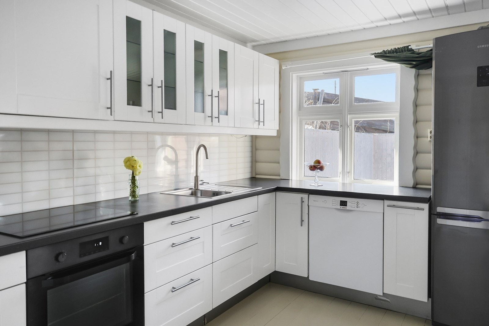 Kjøkkeninnredning med lyse fronter om mørke benkeplater. Galleribilde