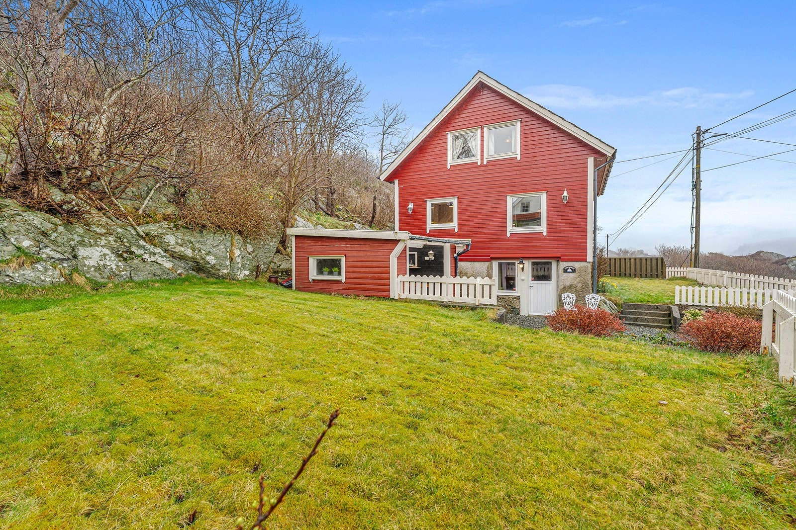 Tomten er pent opparbeidet med plen, noe beplanting, trapper og plattinger i tre og betong. Galleribilde