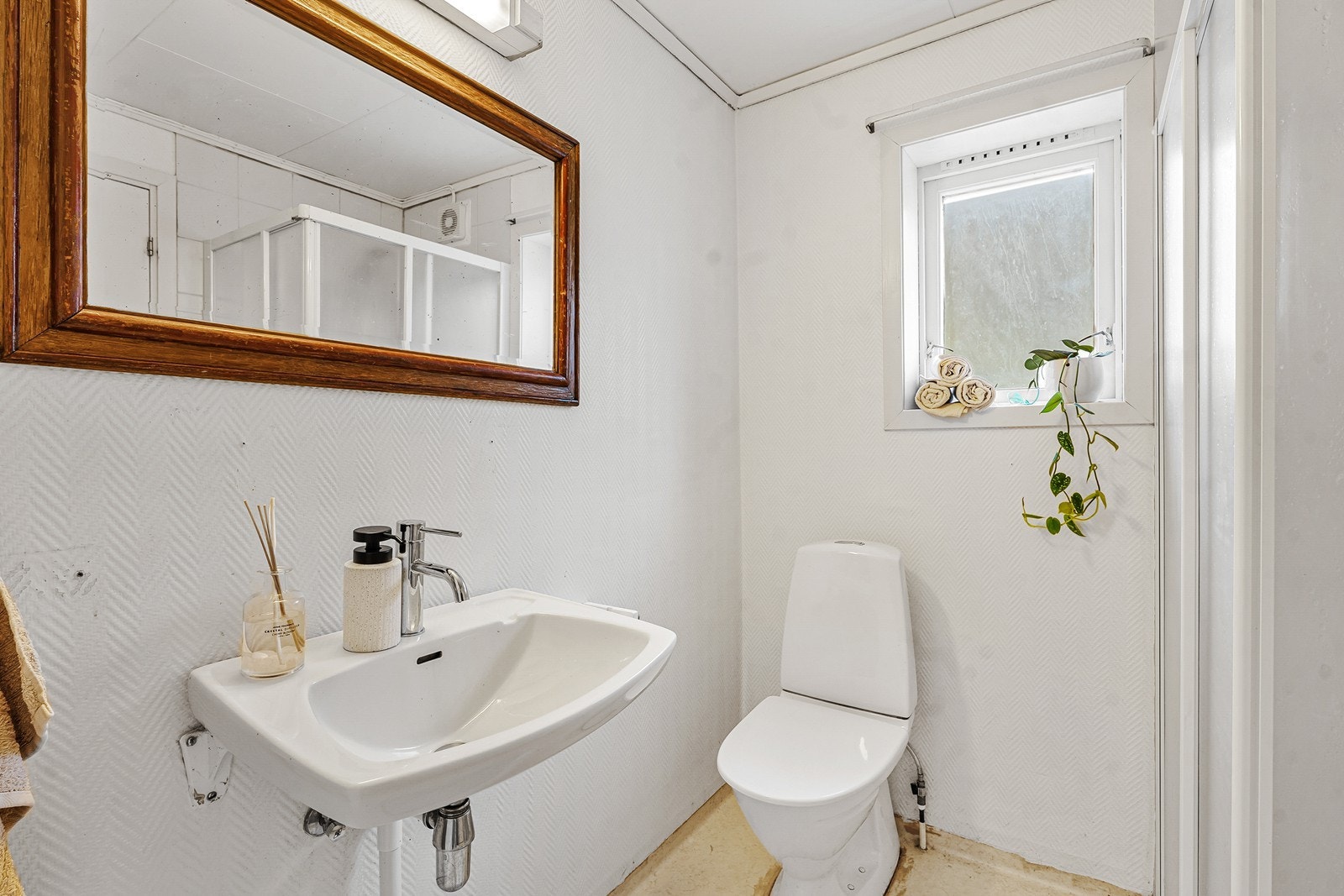 Eldre bad med gulvmonert toalett og enkel servant. Galleribilde