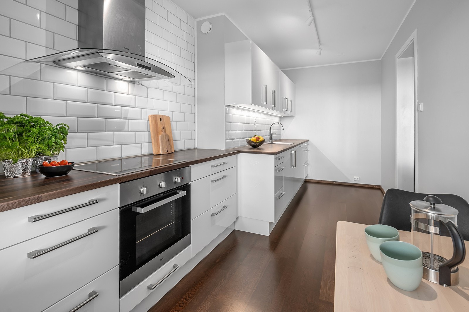 Pent kjøkken med integrerte hvitevarer og plass til spisebord Galleribilde