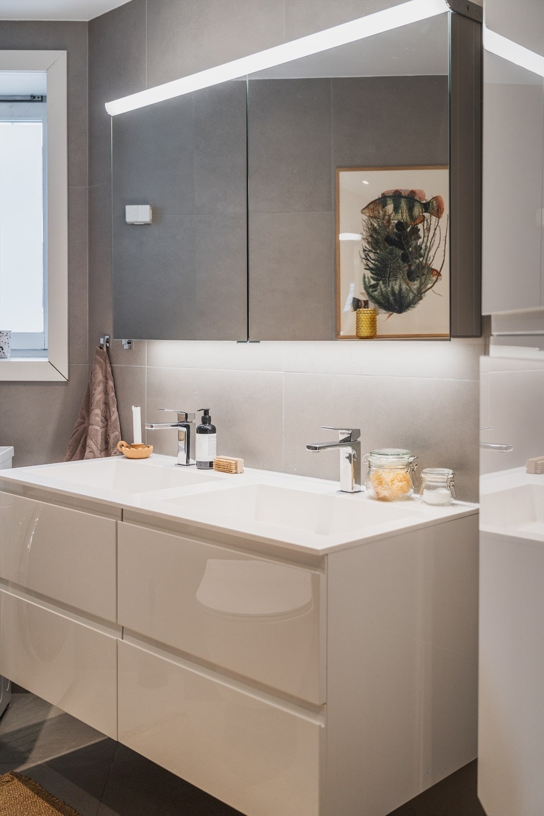 Badet er innredet med vegghengt klosett, servantinnredning, servant med ettgreps blandebatteri, speilskap med belysning og dusjarmatur. Galleribilde