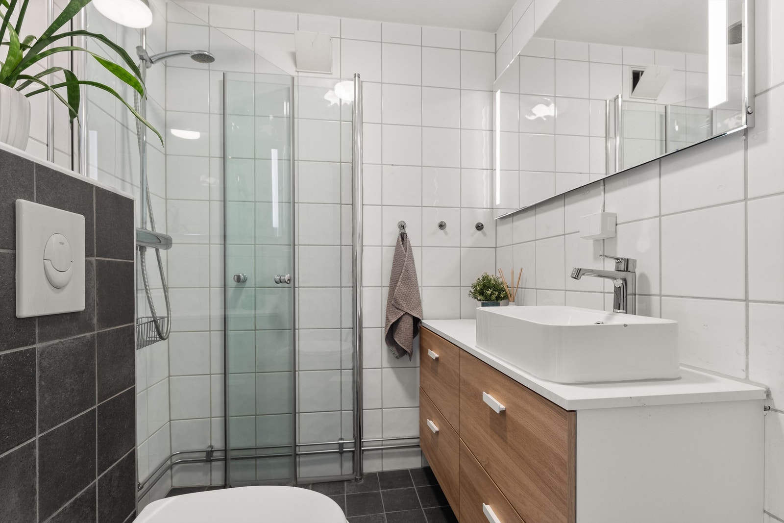 Badet er pent flislagt på gulv og vegger med varme i gulvet. Baderomsinnredningen er fra IKEA fra 2021 og består av vegghengt servantskuffer med servant. Galleribilde