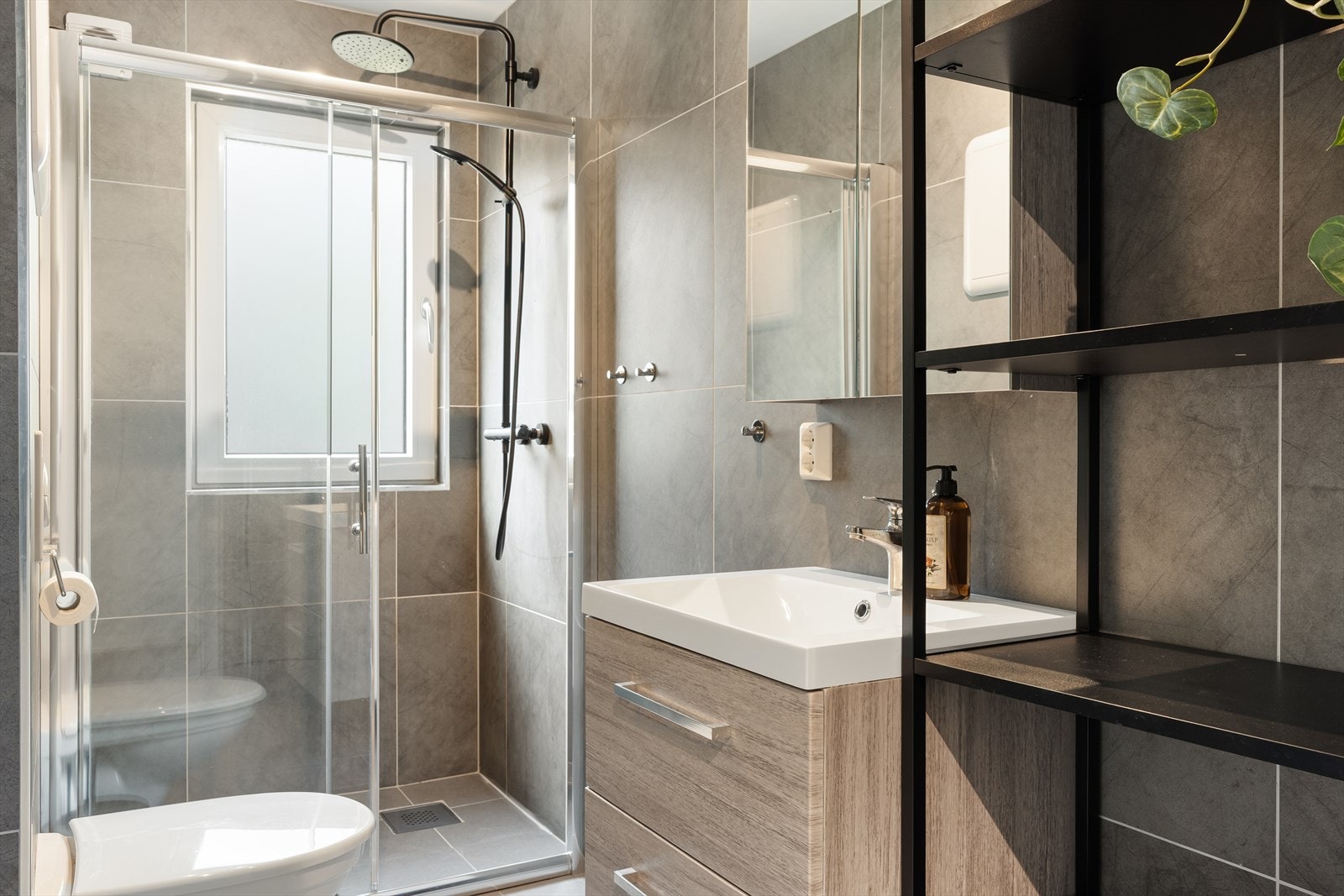 Leiligheten har et rålekkert bad fra ca. 2018/2019. Badet inneholder toalett, dusj med dører av glass, og ellers vask med skapinnredning og speil. Galleribilde
