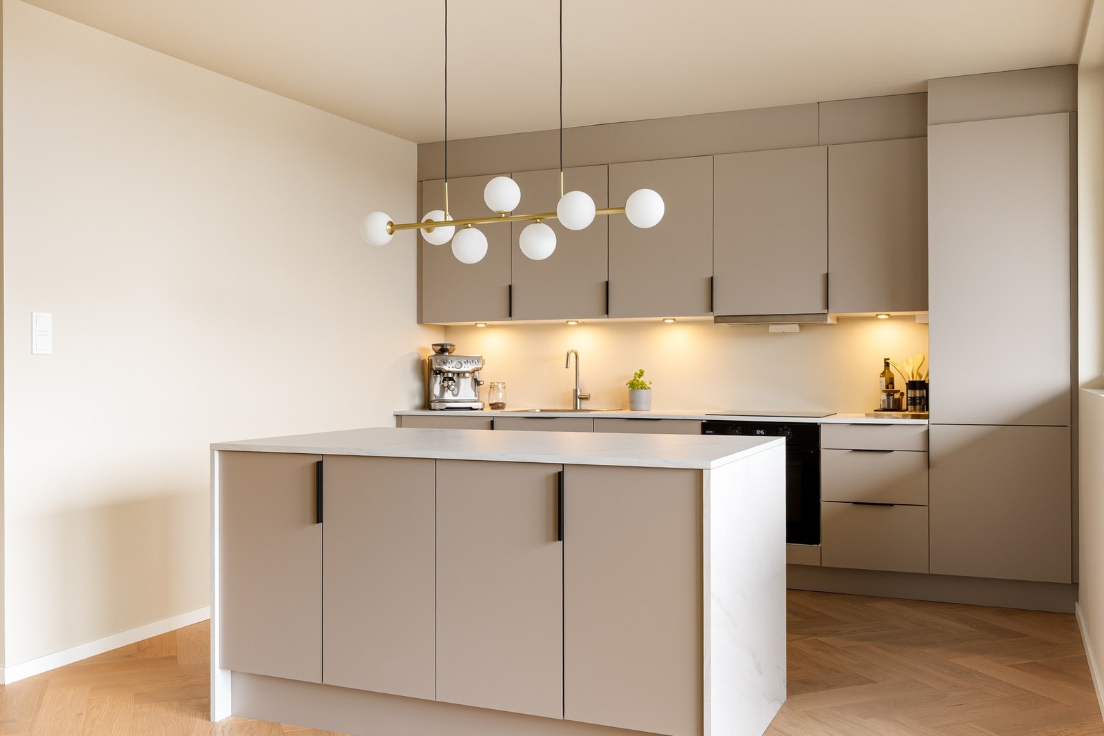 Kjøkkenet er utstyrt med stål oppvaskkum og ventilator, samt integrerte hvitevarer som induksjonsplatetopp, stekeovn, oppvaskmaskin og kjøl- og fryseskap Galleribilde