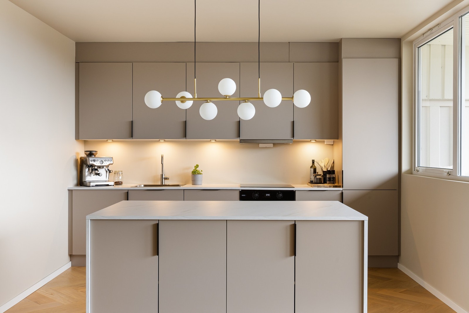 Kjøkkenet fremstår svært moderne og funksjonelt, med slette fronter og en slitesterk laminat benkeplate som gir et stilrent uttrykk. Galleribilde